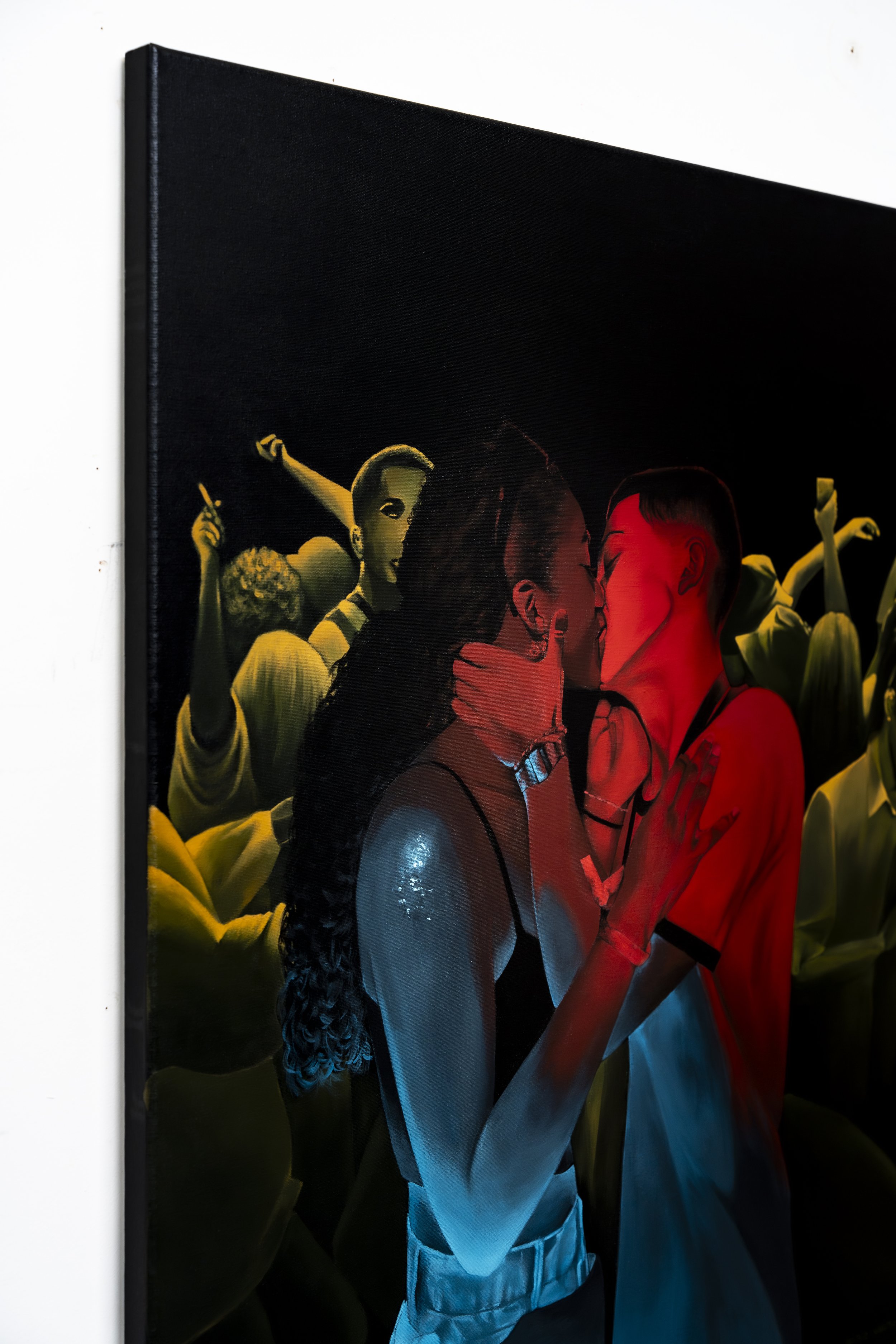 Imagem de um quadro com duas pessoas a beijarem-se, uma em cores azuis e a outra em cores vermelhas, com pessoas fazendo festa ao fundo.