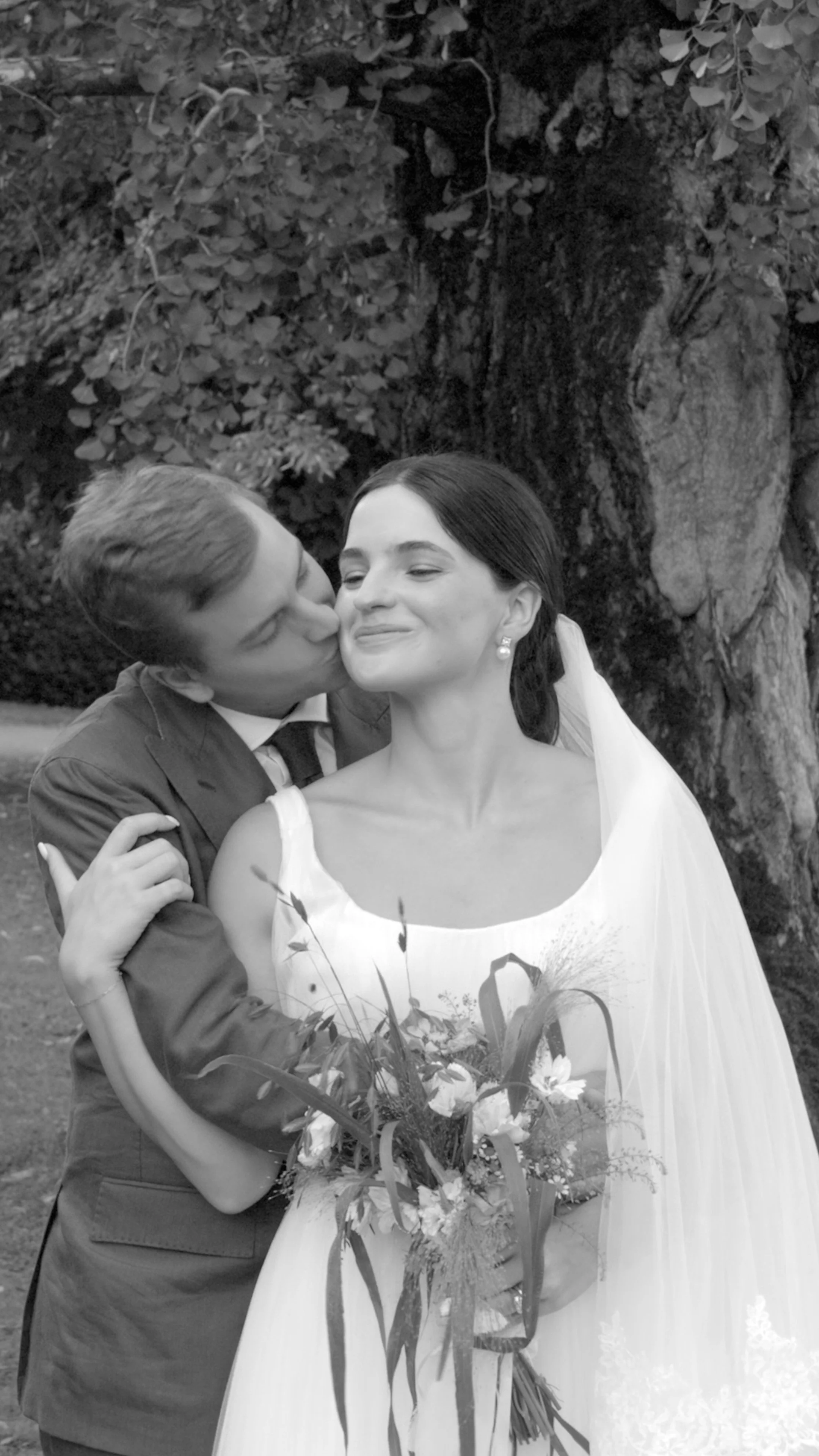 couple on their wedding day, groom kisses brides cheek, photo in black and white