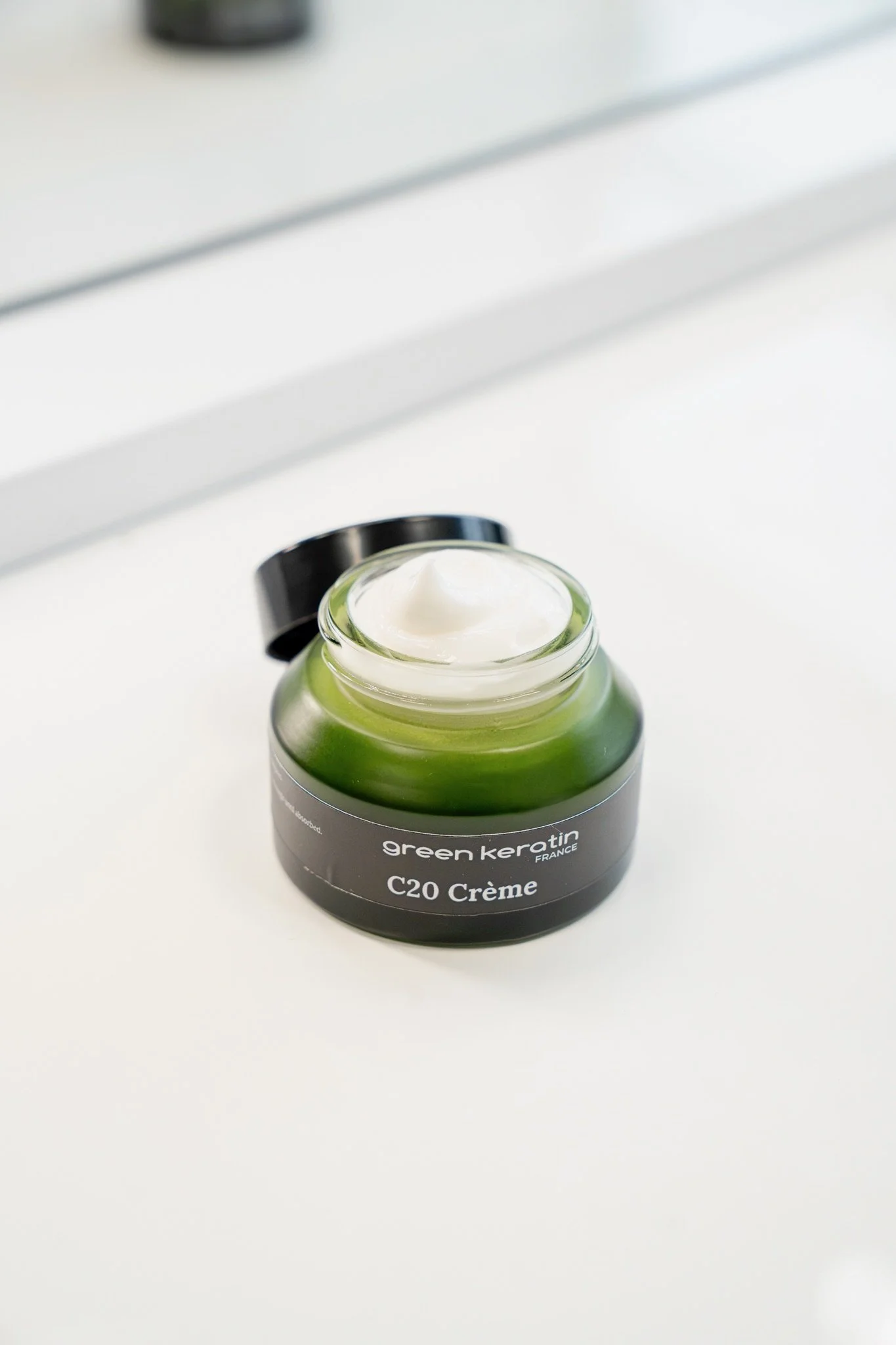 Pot de crème vert de la marque Green Keratin avec le texte C20 Crème sur l'étiquette, placé sur une surface blanche.