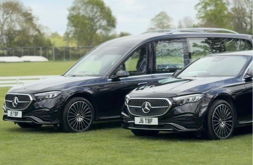 Two black Mercedes-Benz vehicles parked on a grass field with trees and a fence in the background.