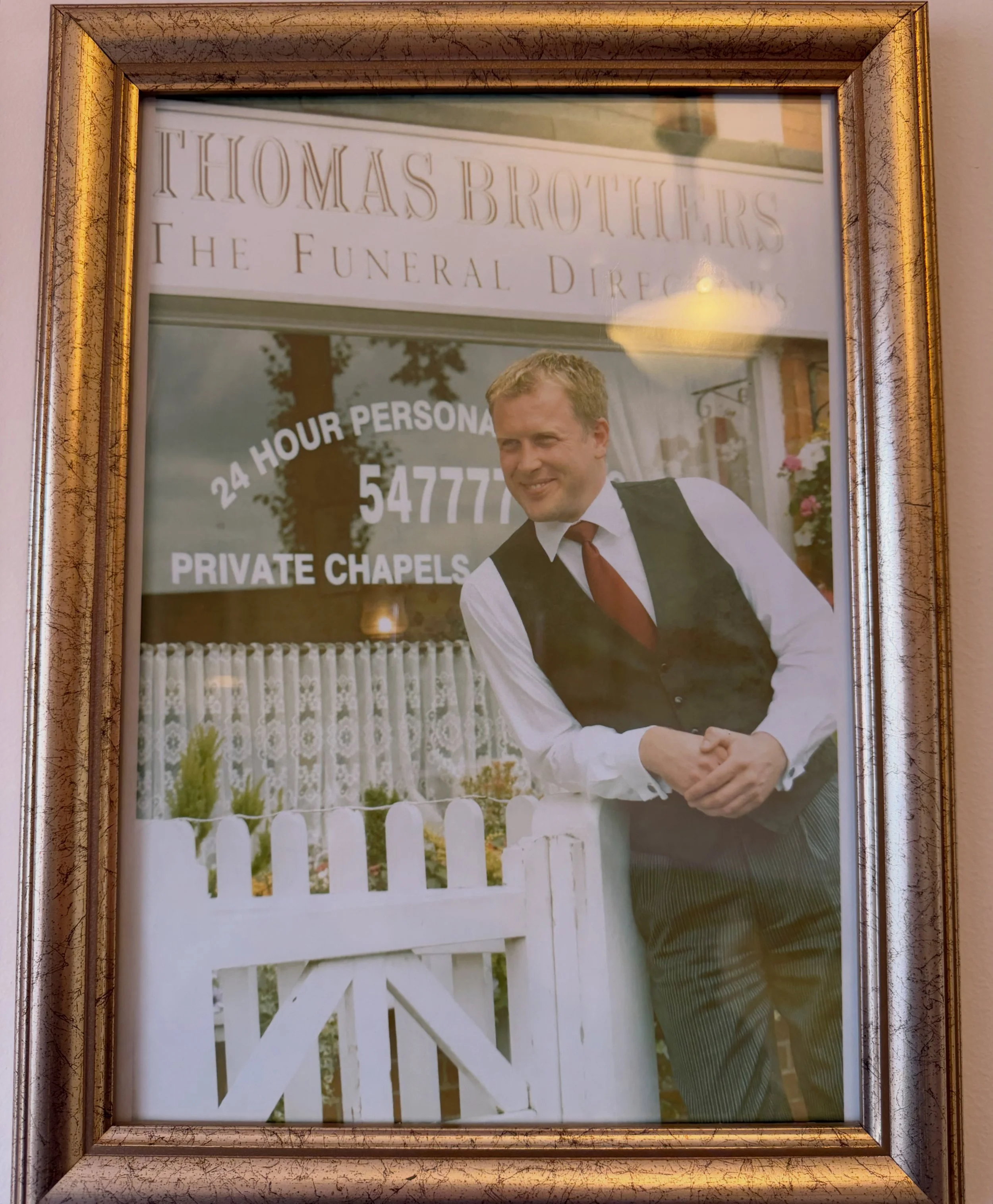 A framed photo of a man Thomas Brothers The Funeral Directors.