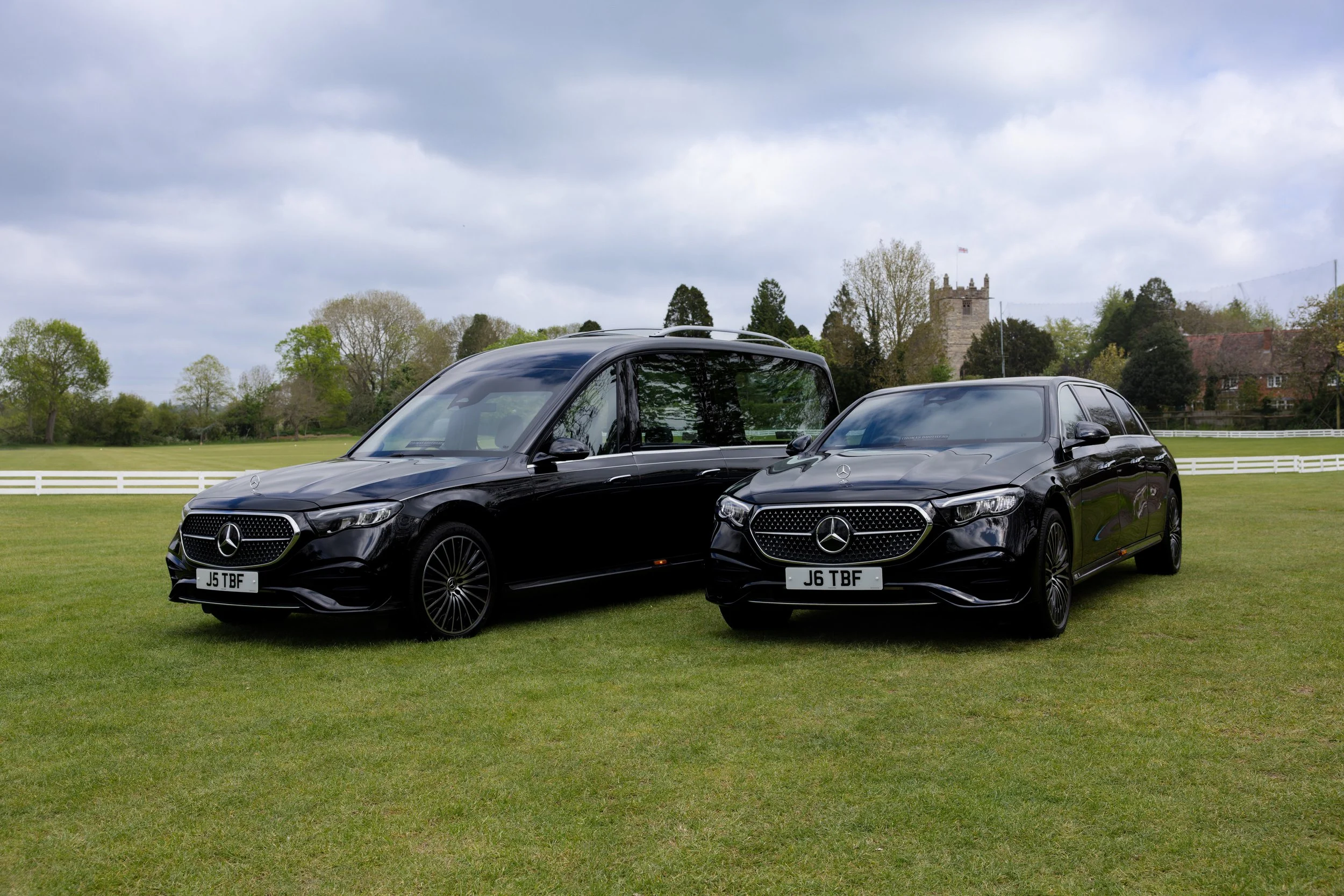Two black hearse and limousine funeral transportation cars.