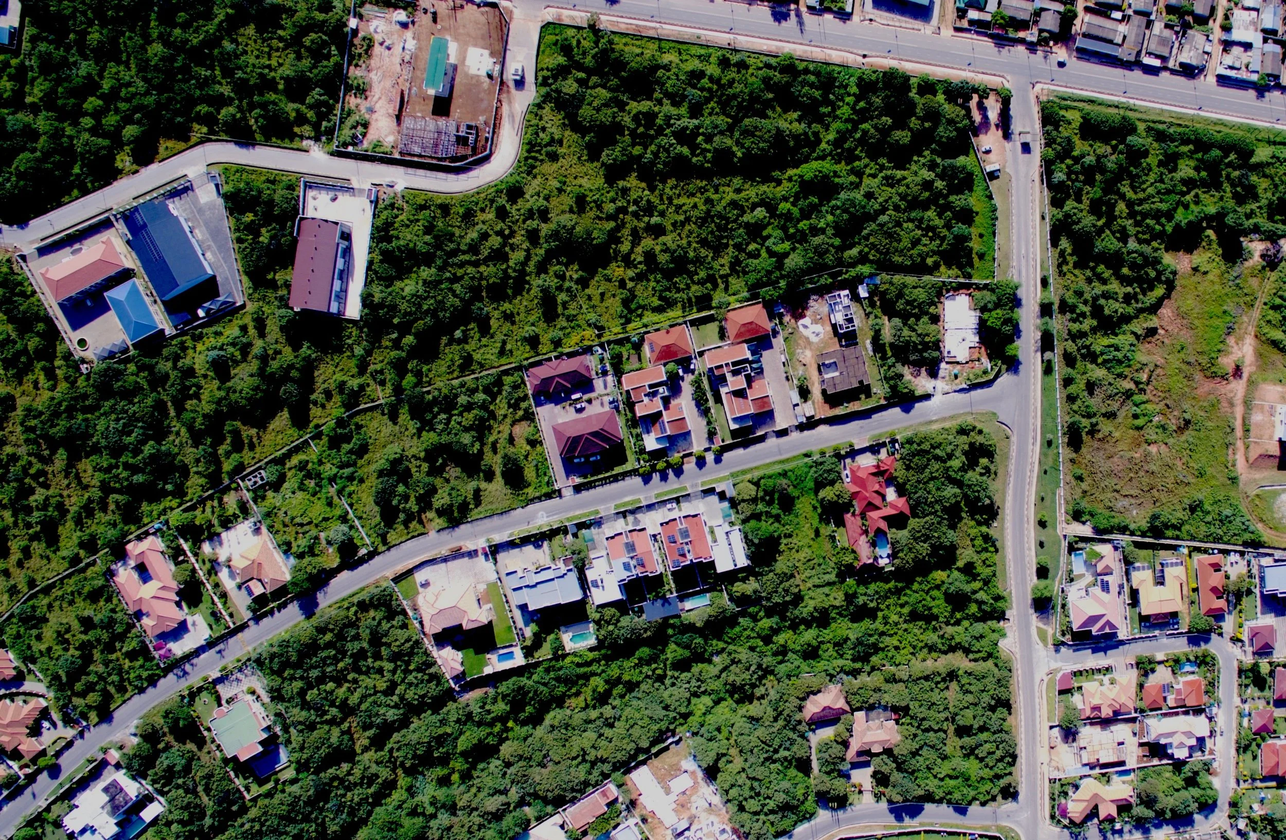 Aerial view of a residential neighborhood with houses, roads, and dense greenery