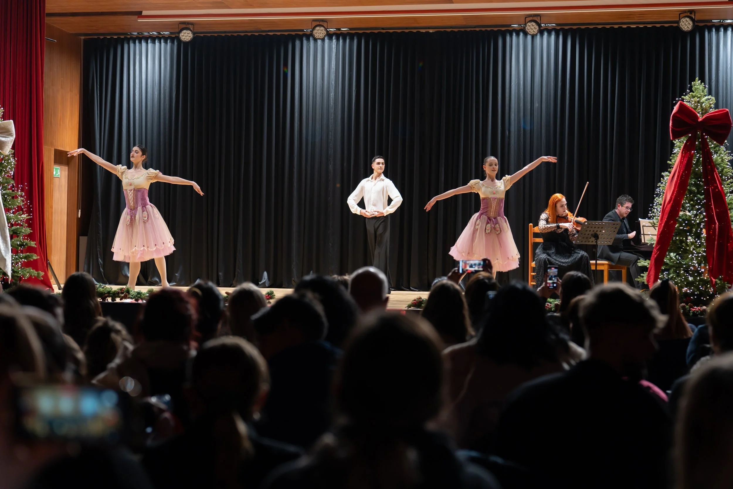Performance on stage featuring ballet dancers and musicians with holiday decorations.