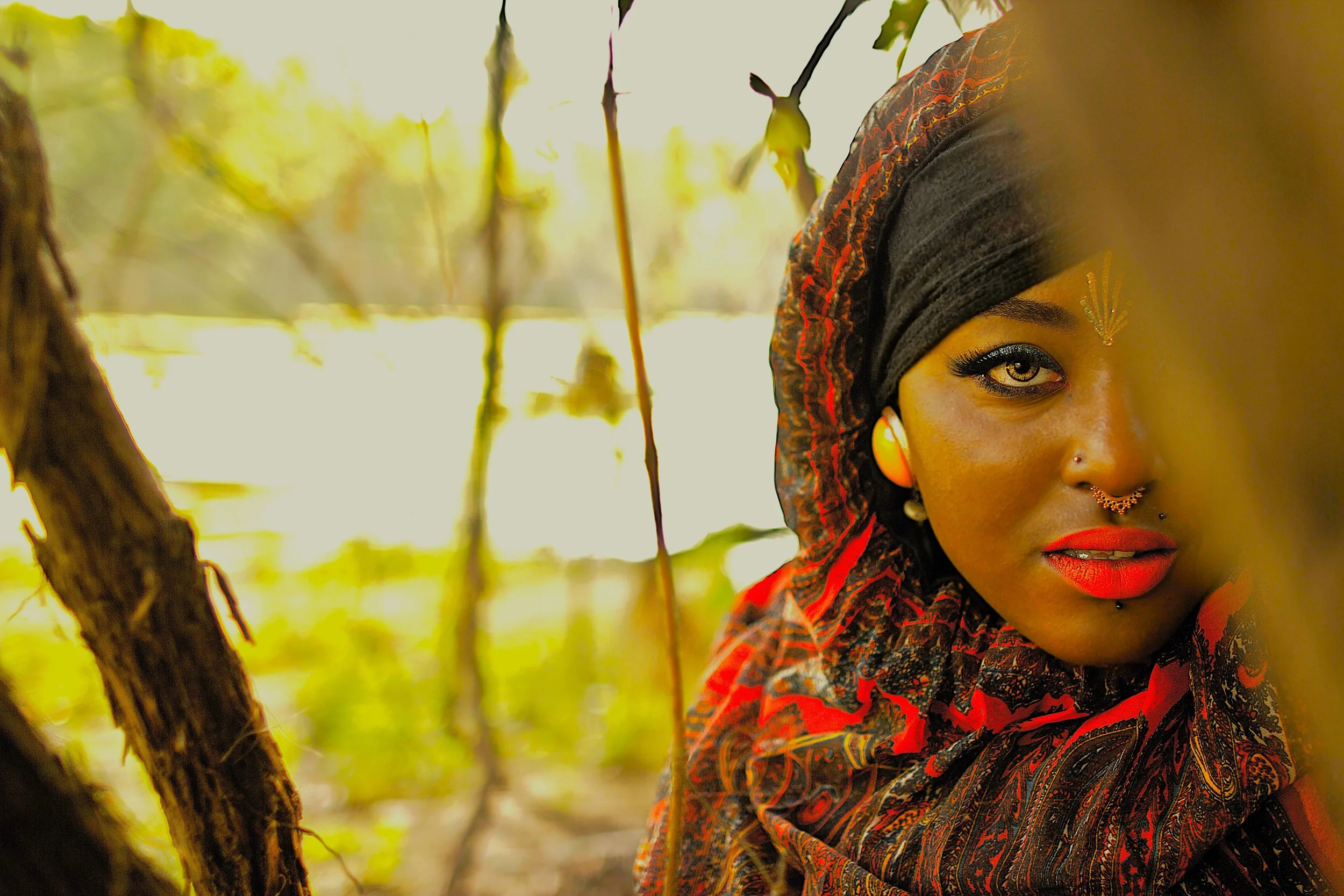 Hidden among the branches along the water’s edge, the Queen of the Golden Sun gazes forward with quiet confidence. Warm golden light illuminates her features while the surrounding shadows and foliage frame her presence, symbolizing strength, awarenes