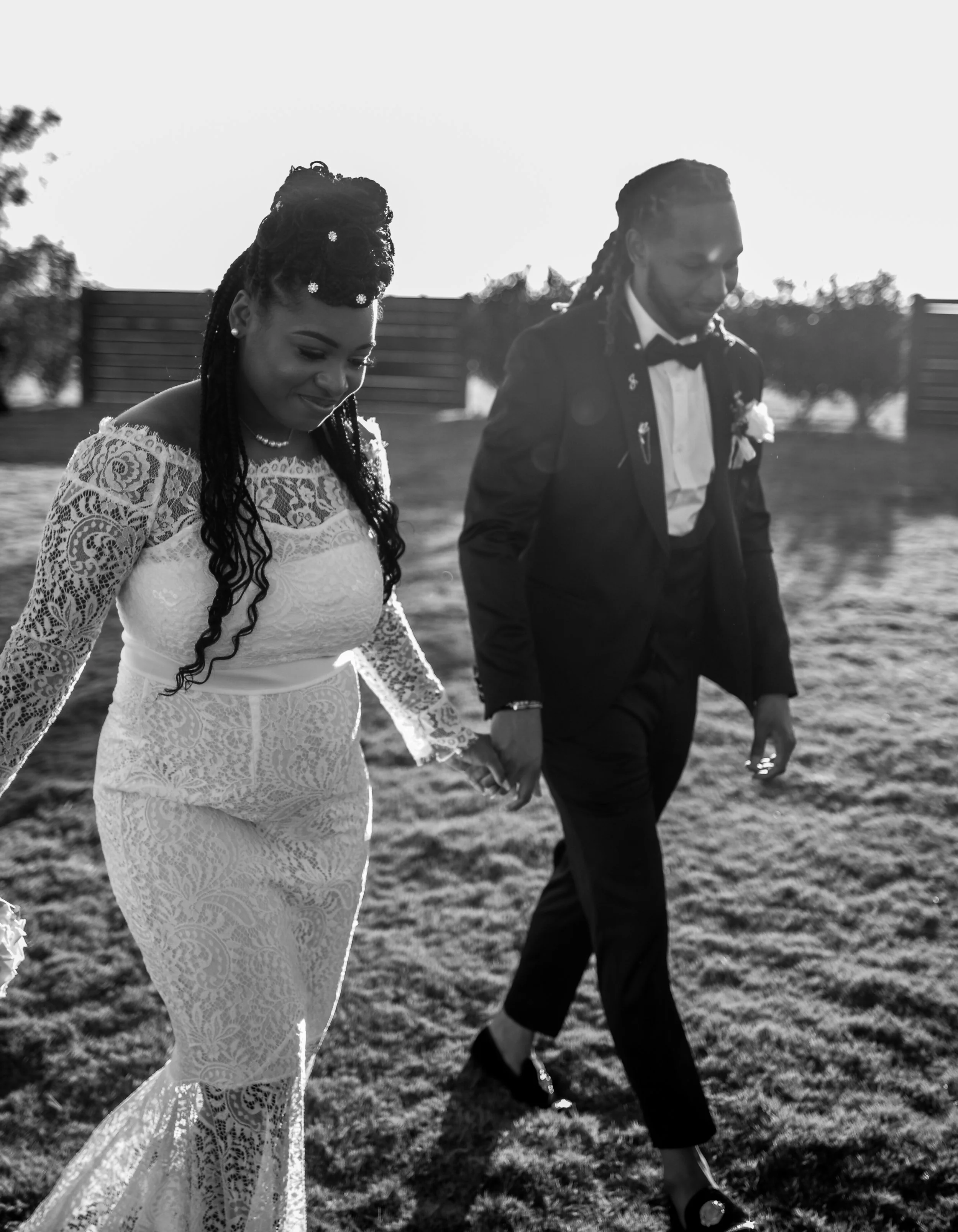 A romantic black-and-white portrait of the newlyweds walking hand in hand across an open field. Captured by Caerus Multimedia, this moment highlights the timeless elegance and natural storytelling style of Austin wedding photography.