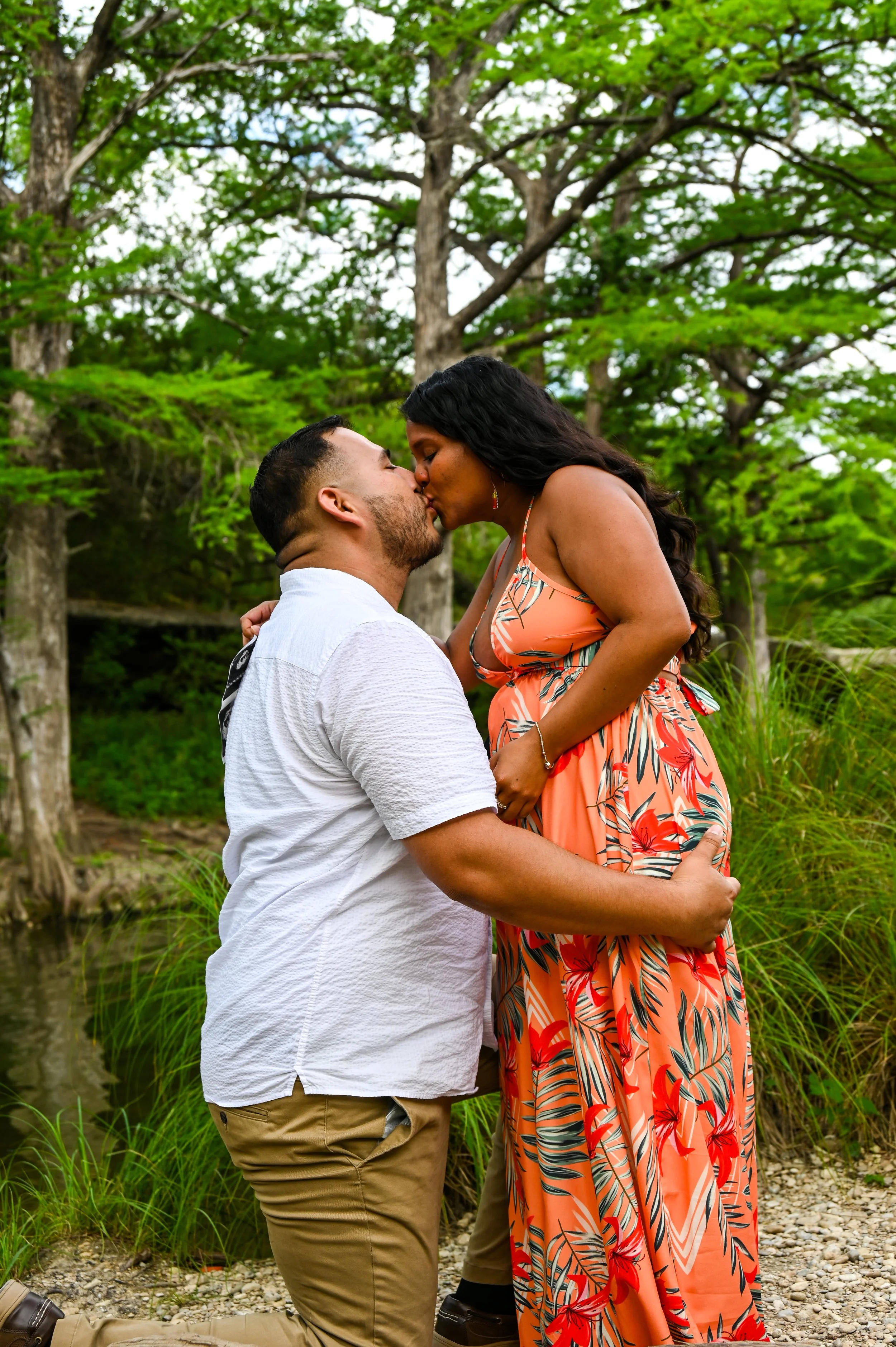 A romantic engagement photo of a couple sharing their first kiss after the proposal during a scenic outdoor engagement photography session in Austin, Texas captured by Caerus Multimedia.