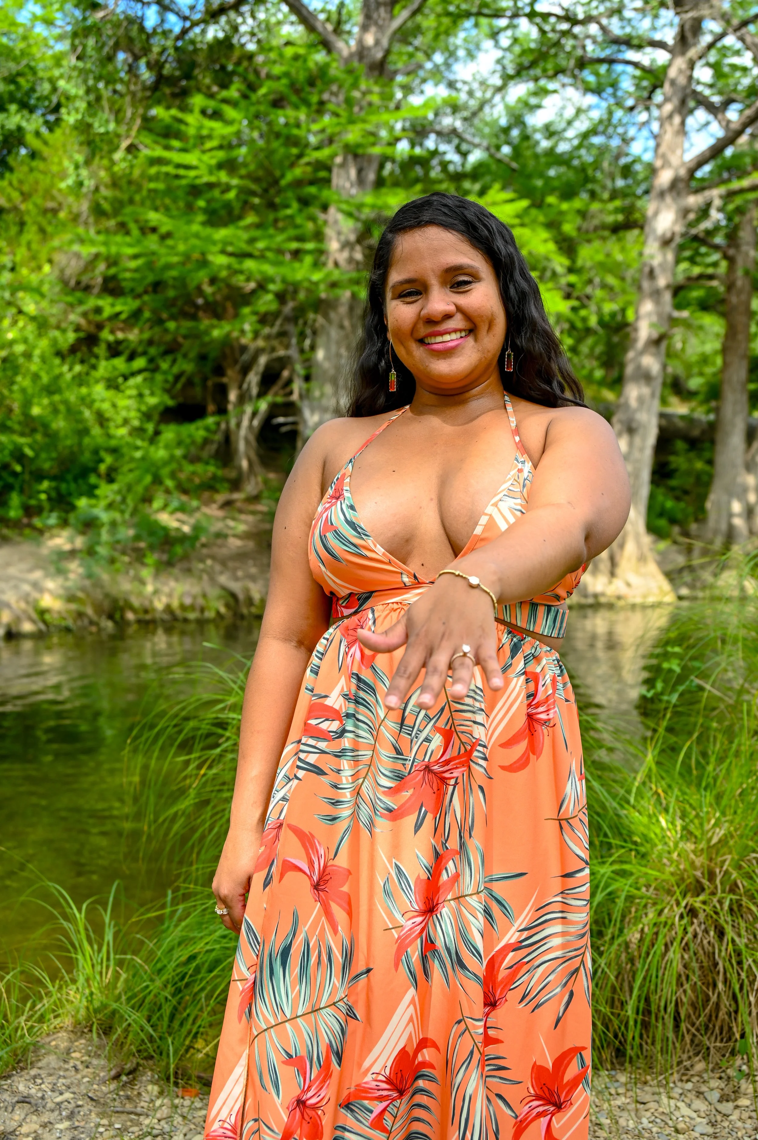 A vibrant engagement portrait of a newly engaged bride-to-be proudly showing her engagement ring during a natural outdoor engagement session in Austin, Texas captured by Caerus Multimedia.