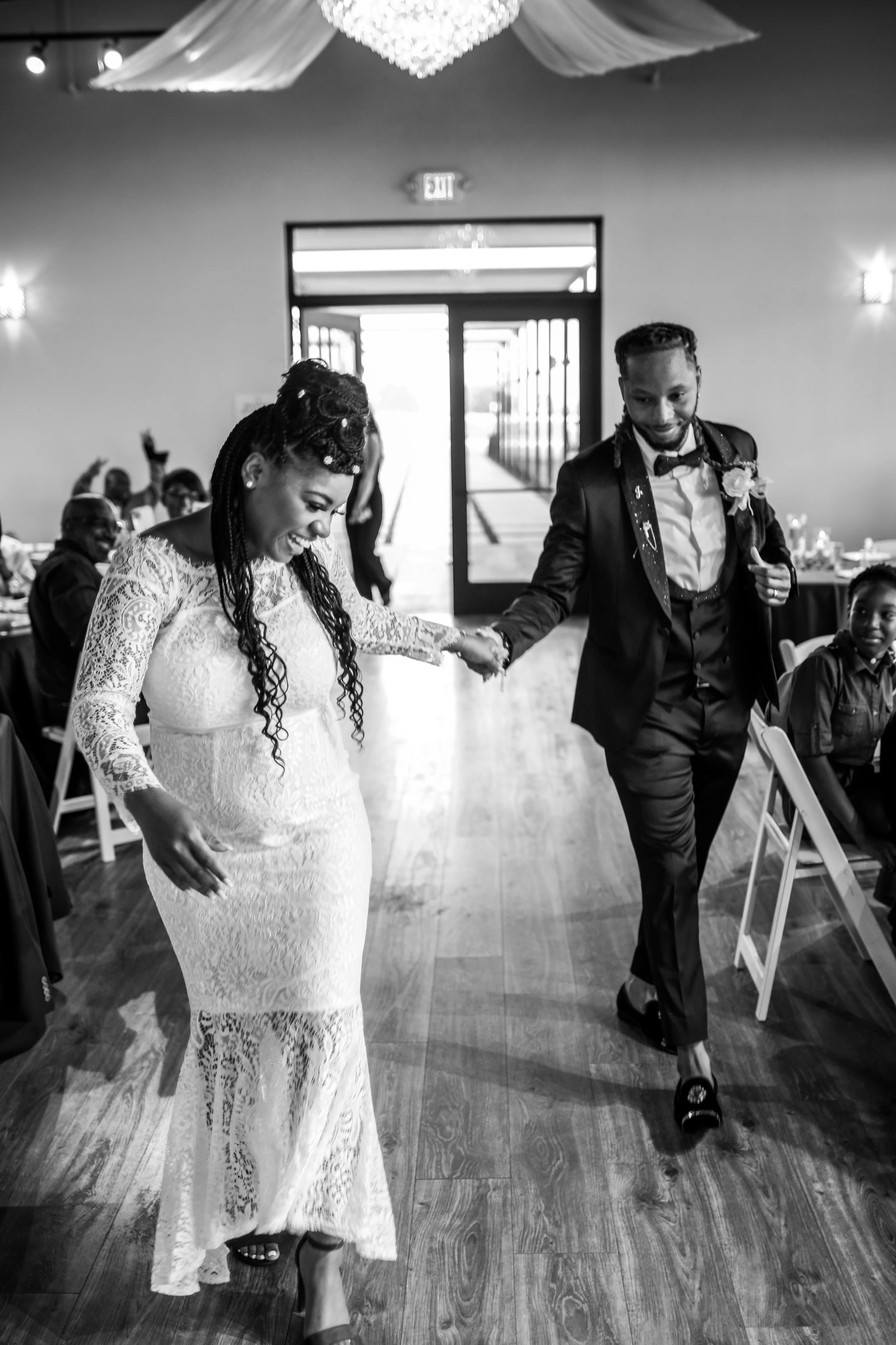 The newlyweds dance into their reception during their grand entrance as guests celebrate their arrival. This candid moment showcases the lively atmosphere and storytelling approach of Caerus Multimedia wedding photography in Austin, Texas.