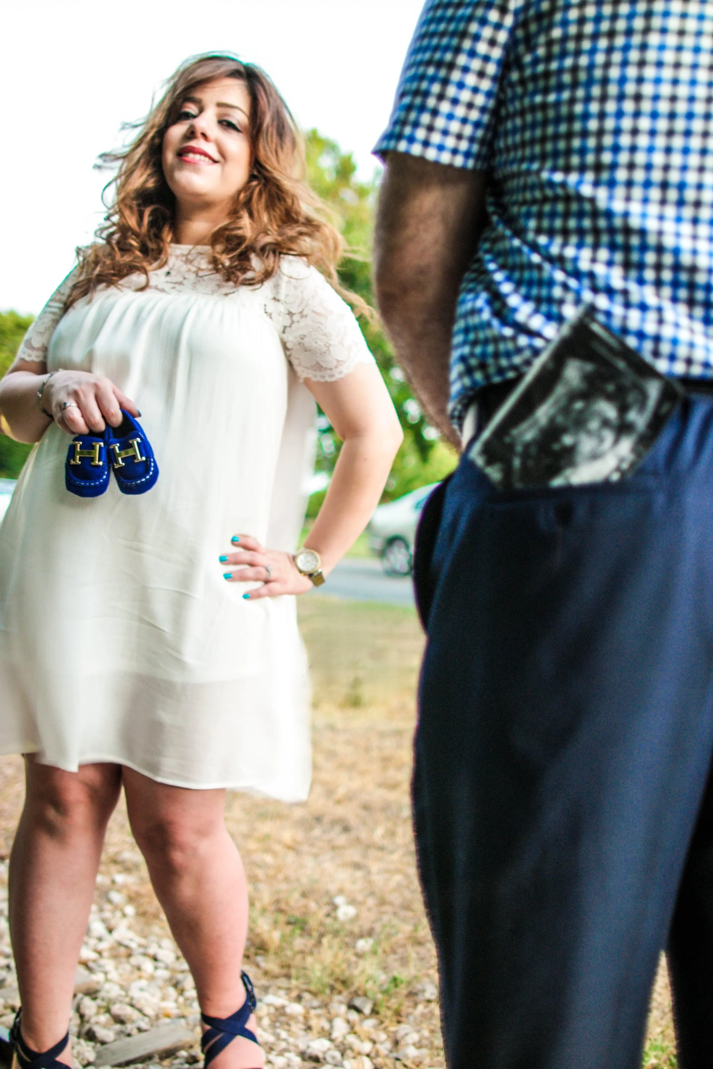 Creative pregnancy announcement portrait featuring baby shoes and an ultrasound photo during a maternity photography session in Austin, Texas captured by Caerus Multimedia.