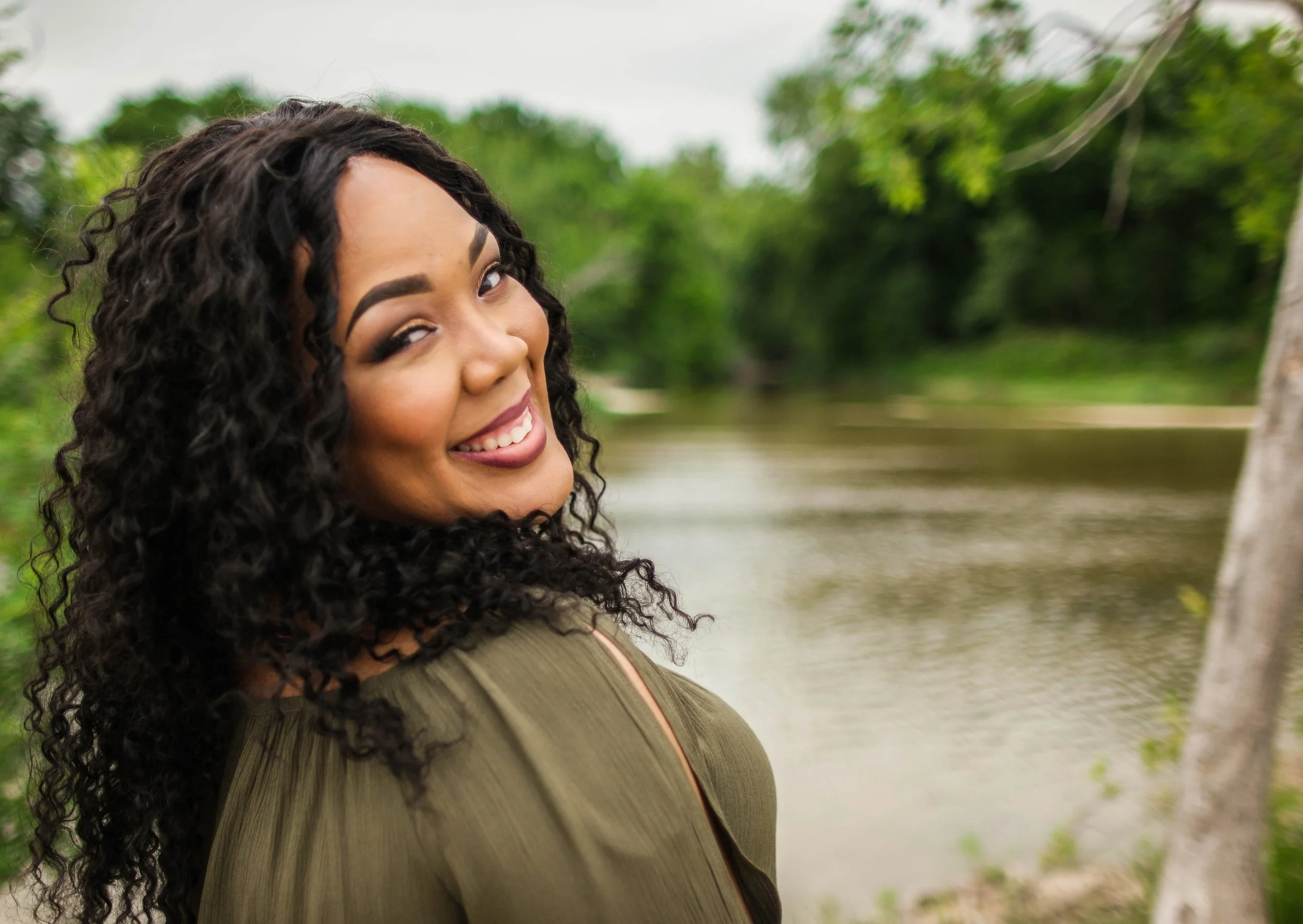 A relaxed outdoor portrait featuring natural light and lush greenery. The soft tones and candid expression create an inviting portrait style that Caerus Multimedia is known for during lifestyle sessions around Austin.