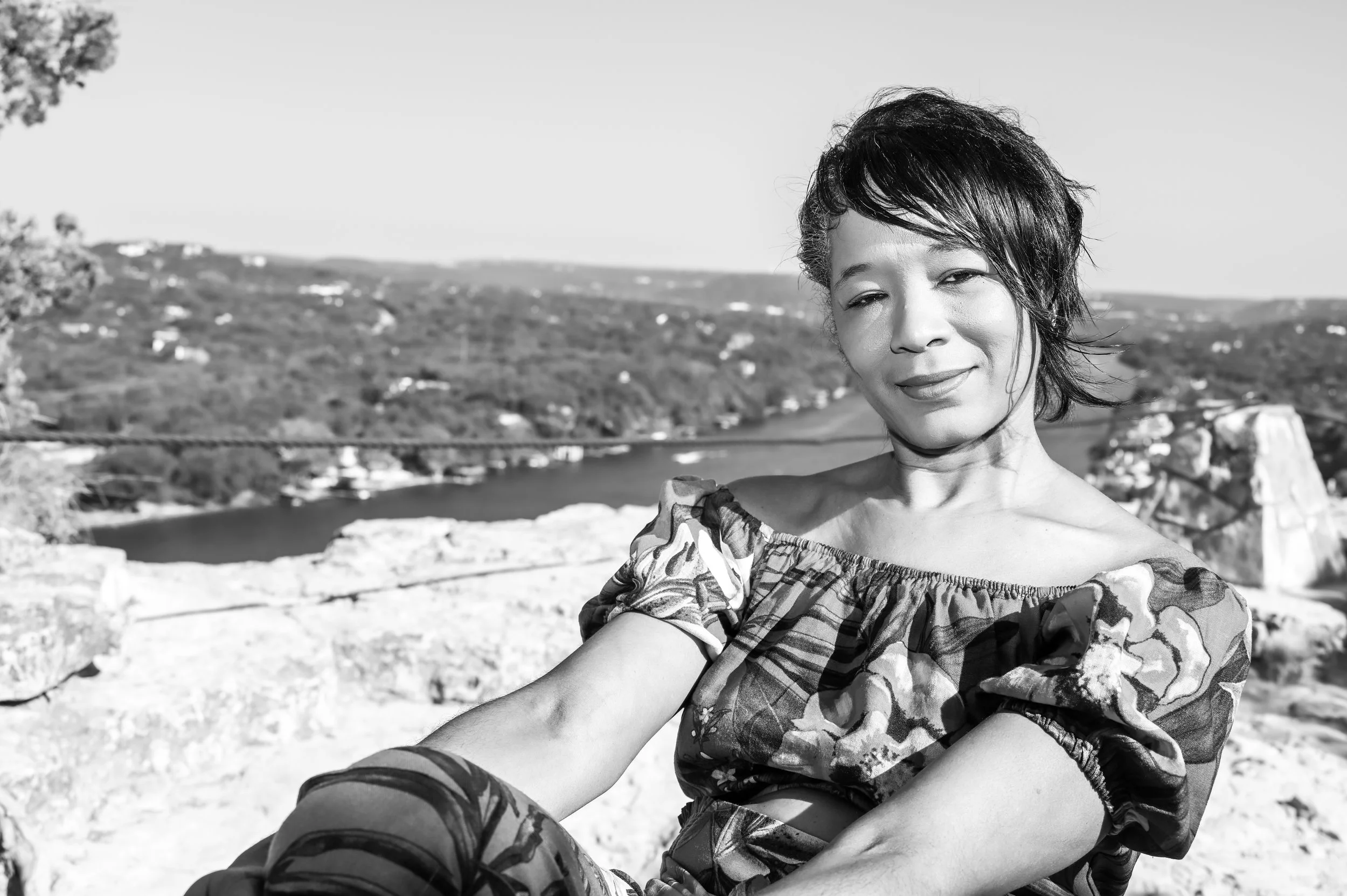 Captured at a scenic overlook high above the Colorado River in Austin, this portrait blends natural beauty with confident portrait styling. The sweeping Texas Hill Country view creates a dramatic backdrop while the relaxed pose keeps the portrait fee