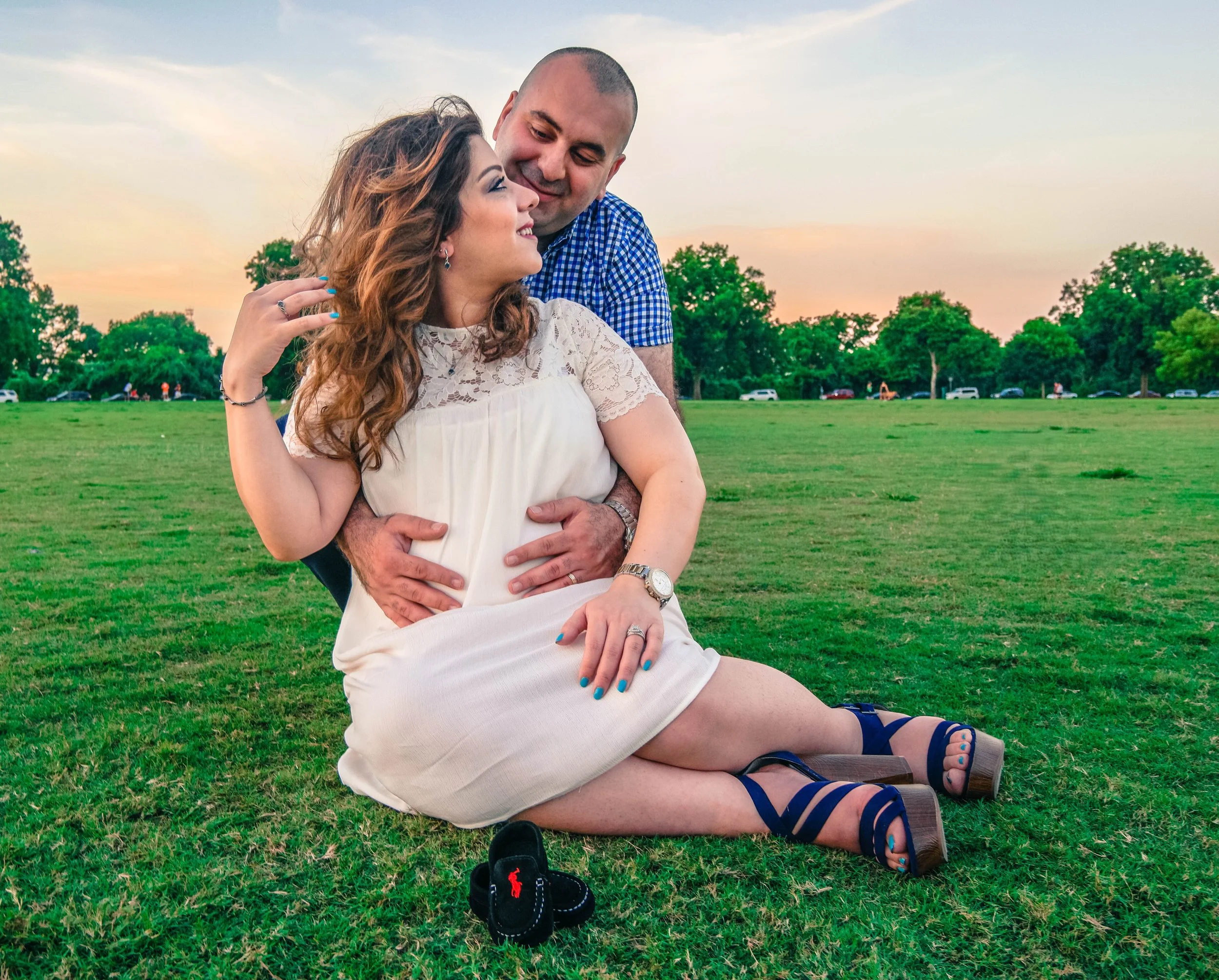 Expecting parents sharing a romantic moment in an open field during a maternity photography session in Austin, Texas. This pregnancy portrait highlights the excitement of welcoming a new baby and was captured by Austin maternity photographer Caerus M