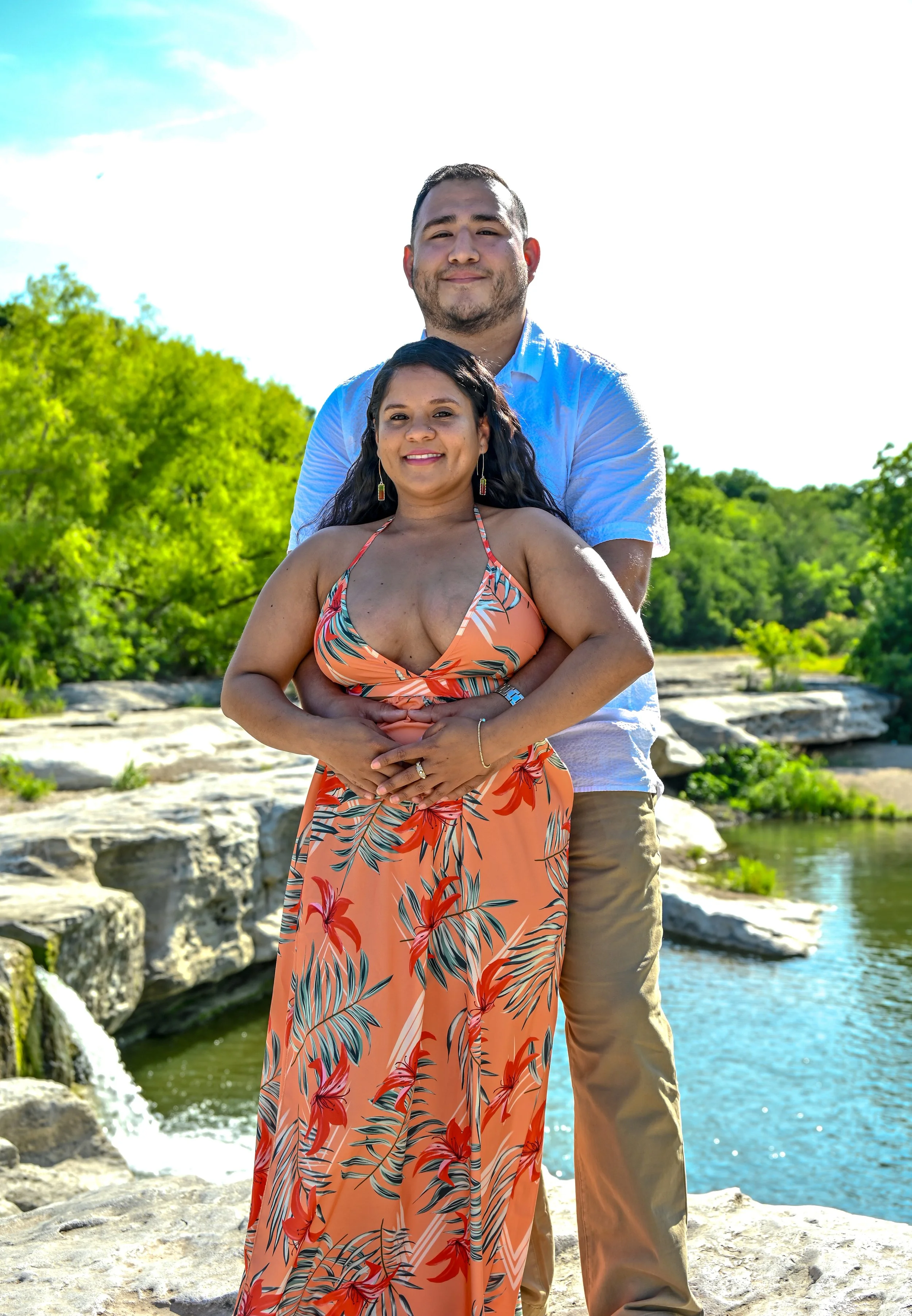 Couple posing together near a waterfall during a romantic outdoor maternity photography session in Austin, Texas photographed by Caerus Multimedia.