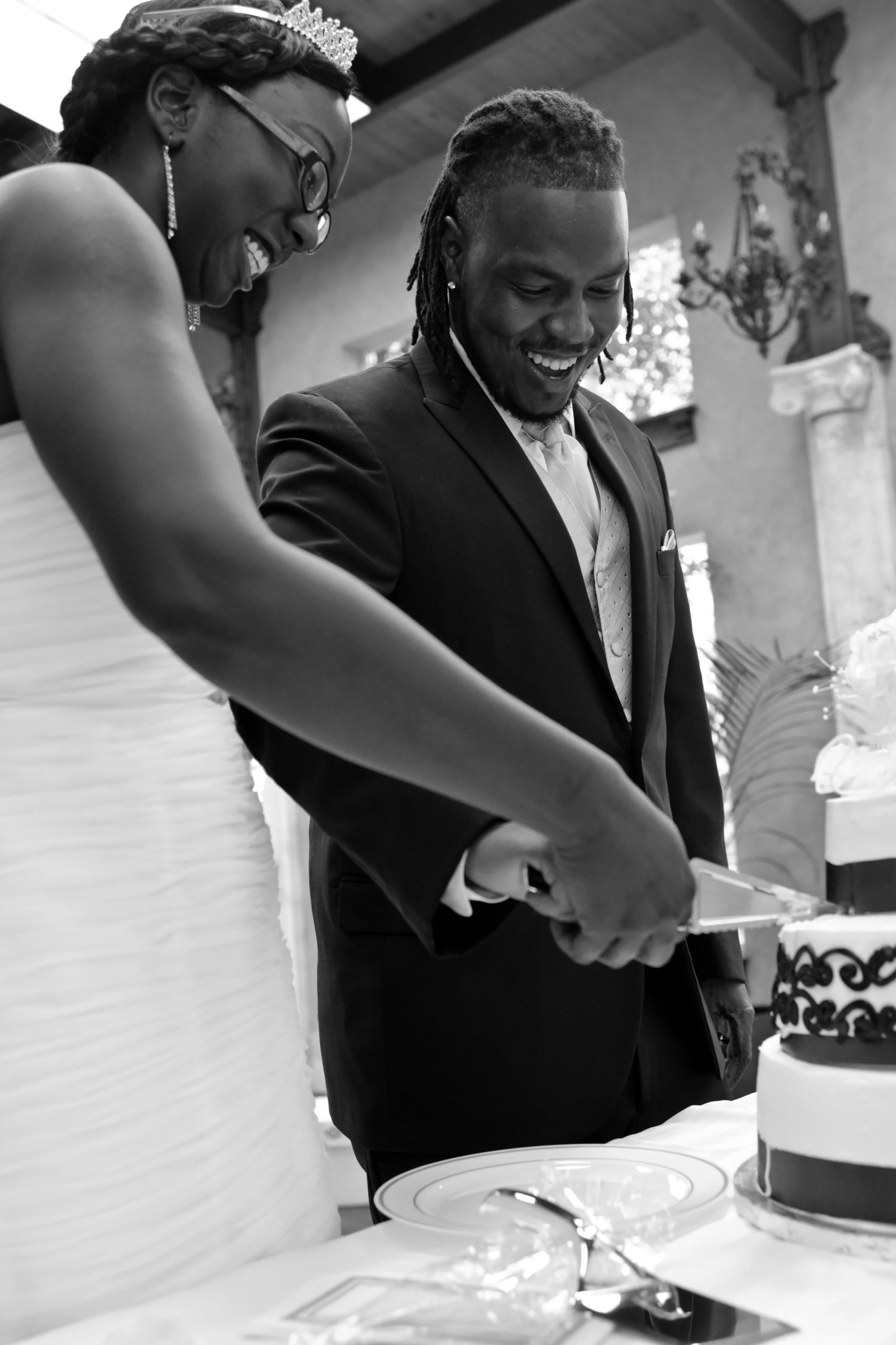 The bride and groom laugh together while cutting their wedding cake during the reception celebration. Photographed by Caerus Multimedia, this image captures the genuine emotions and joyful moments of an Austin wedding reception.
