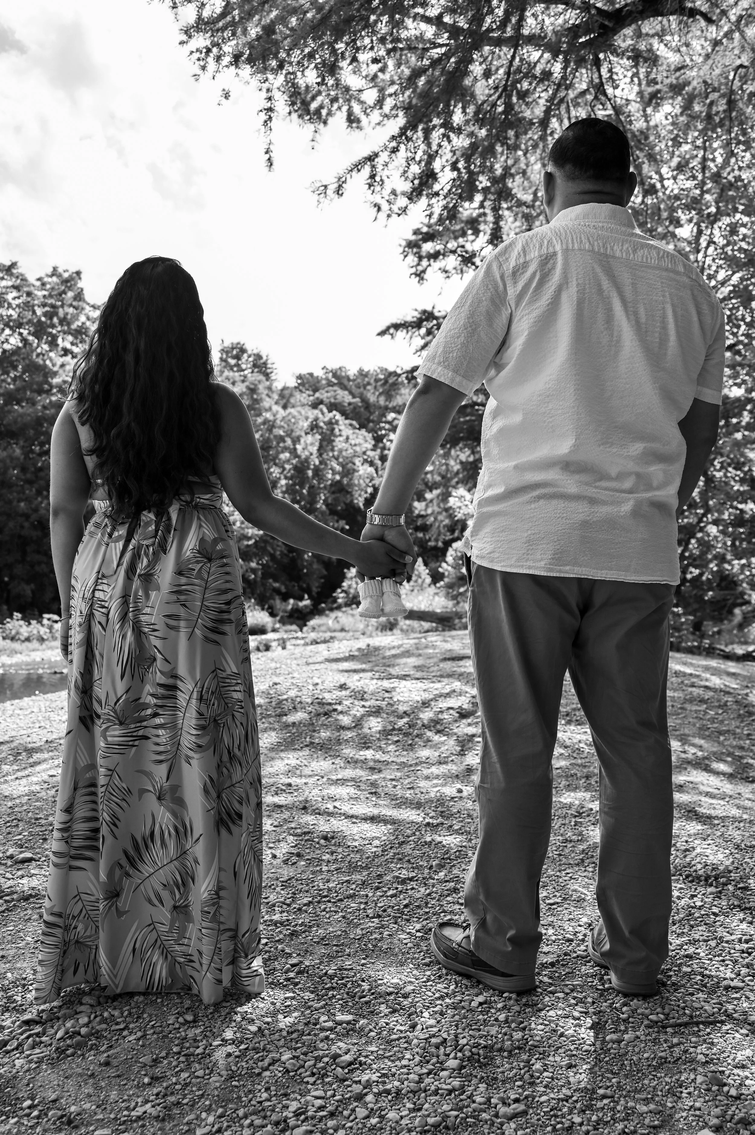 Expecting parents walking together along a scenic riverside during a natural maternity photography session in Austin, Texas captured by Caerus Multimedia.