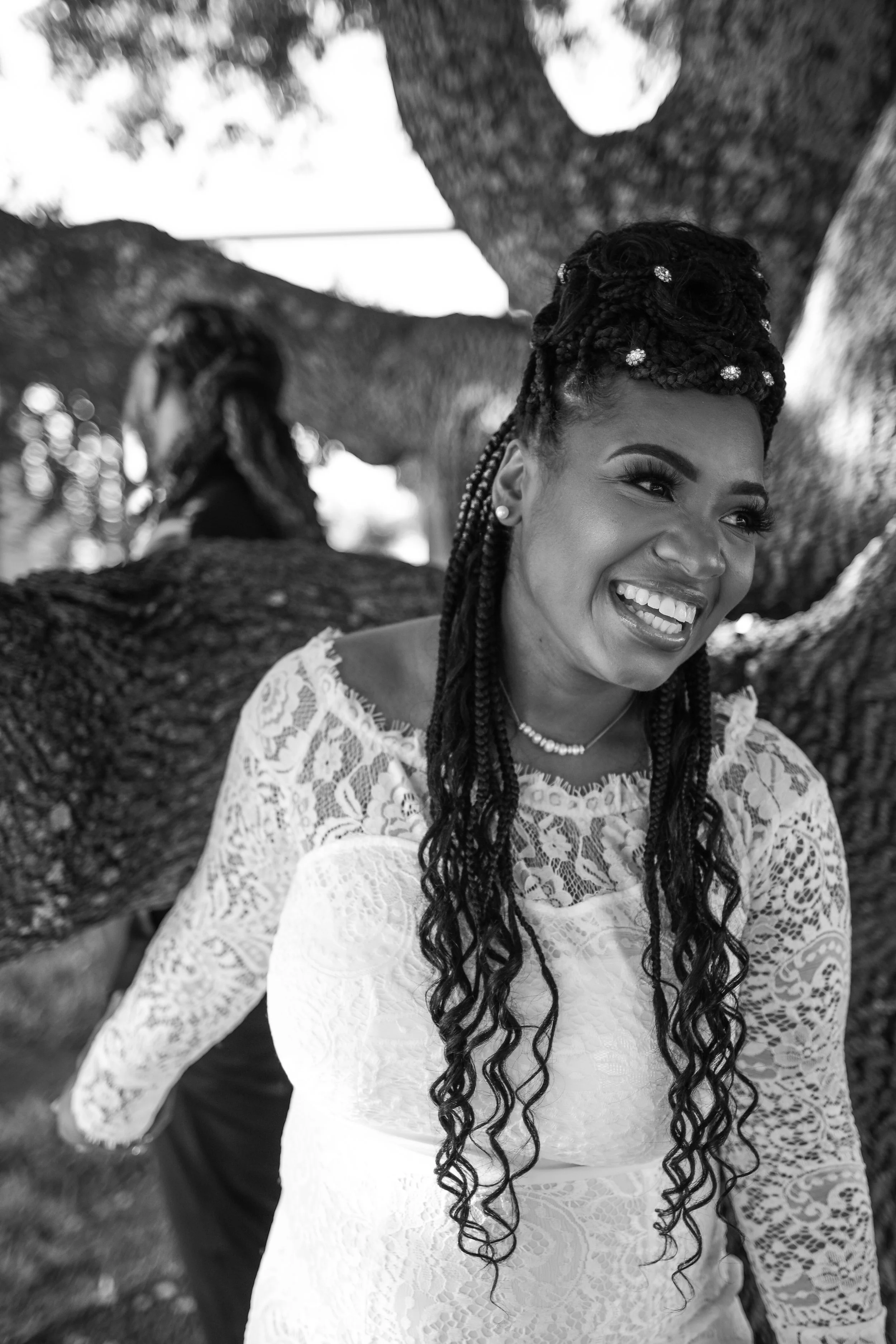 The bride shares a joyful laugh while surrounded by the branches of a sunlit oak tree during her wedding day portraits. This candid moment reflects the authentic, emotional style of Caerus Multimedia wedding photography in Austin, Texas.