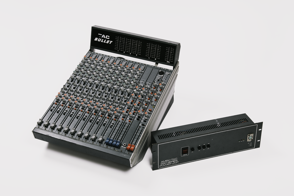 Table de mixage audio professionnelle analogique après réparation et révision, nombreux faders et potentiomètres, et alimentation externe 