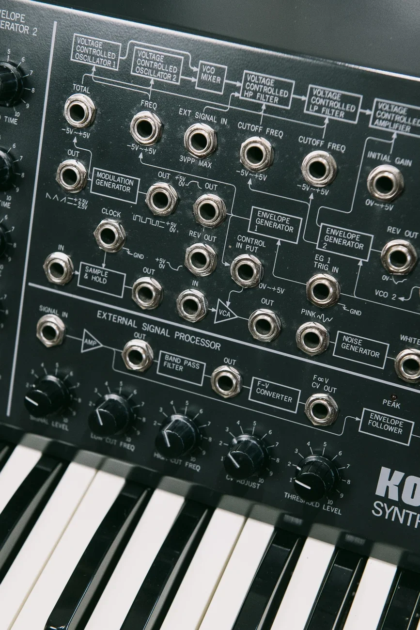 Synthétiseur analogique avec des knobs, des connecteurs et un schéma électronique imprimé sur sa surface.