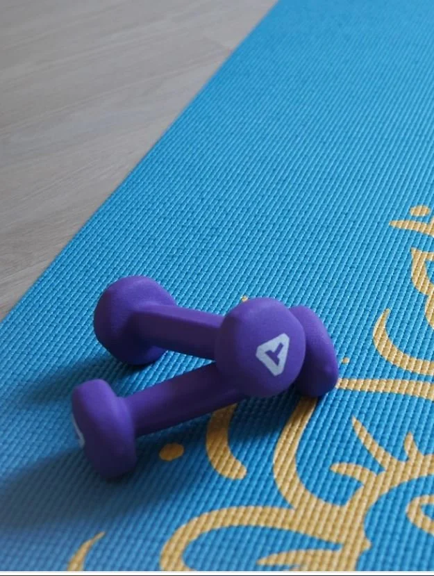 Altères posées sur un tapis de sport, illustrant l’importance du mouvement dans l’accompagnement naturopathique : énergie, circulation, gestion du stress, mobilité et soutien global du terrain.
