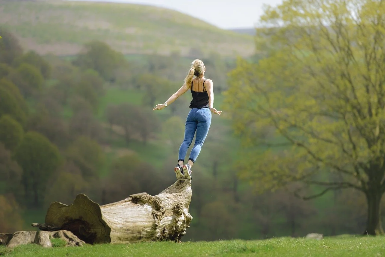 Femme sereine en pleine nature, symbolisant le chemin vers l’équilibre. Illustration de la citation “l’équilibre n’est pas un état, c’est un chemin”, au cœur de l’accompagnement naturopathique fondé sur l’écoute, la douceur et l’harmonie.