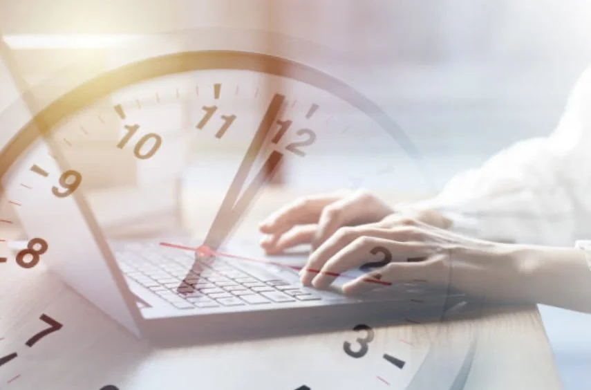 Close-up of a person's hands typing on a laptop with a large clock overlay showing time close to 12:02.