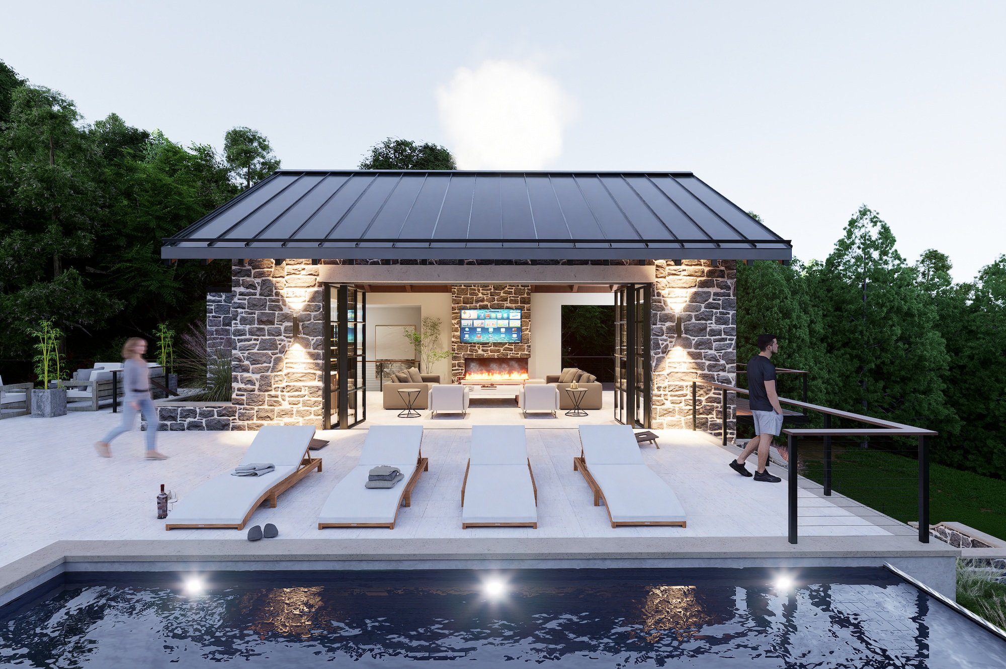 Modern outdoor pool house at sunset with chaise lounges, a house with stone walls and large glass doors, a fireplace, and people walking nearby surrounded by trees.