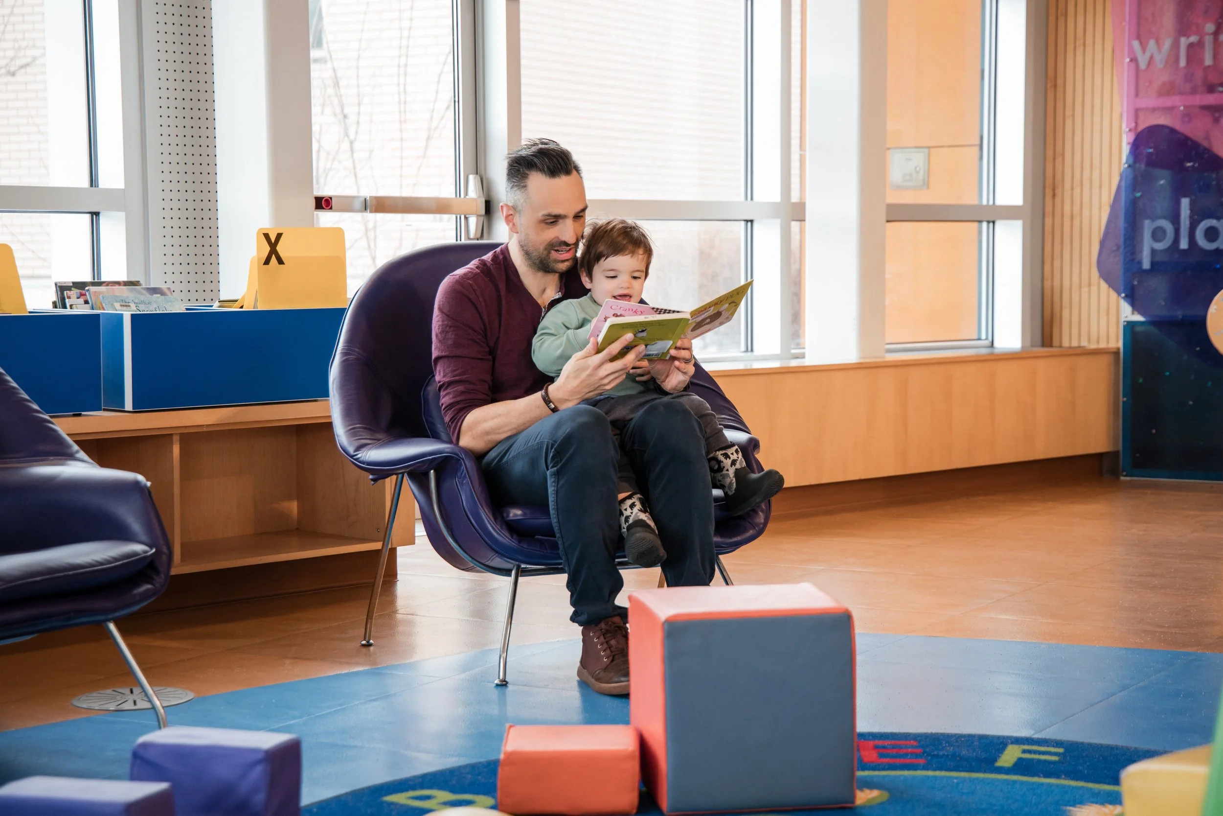 Adult and child reading together in a library