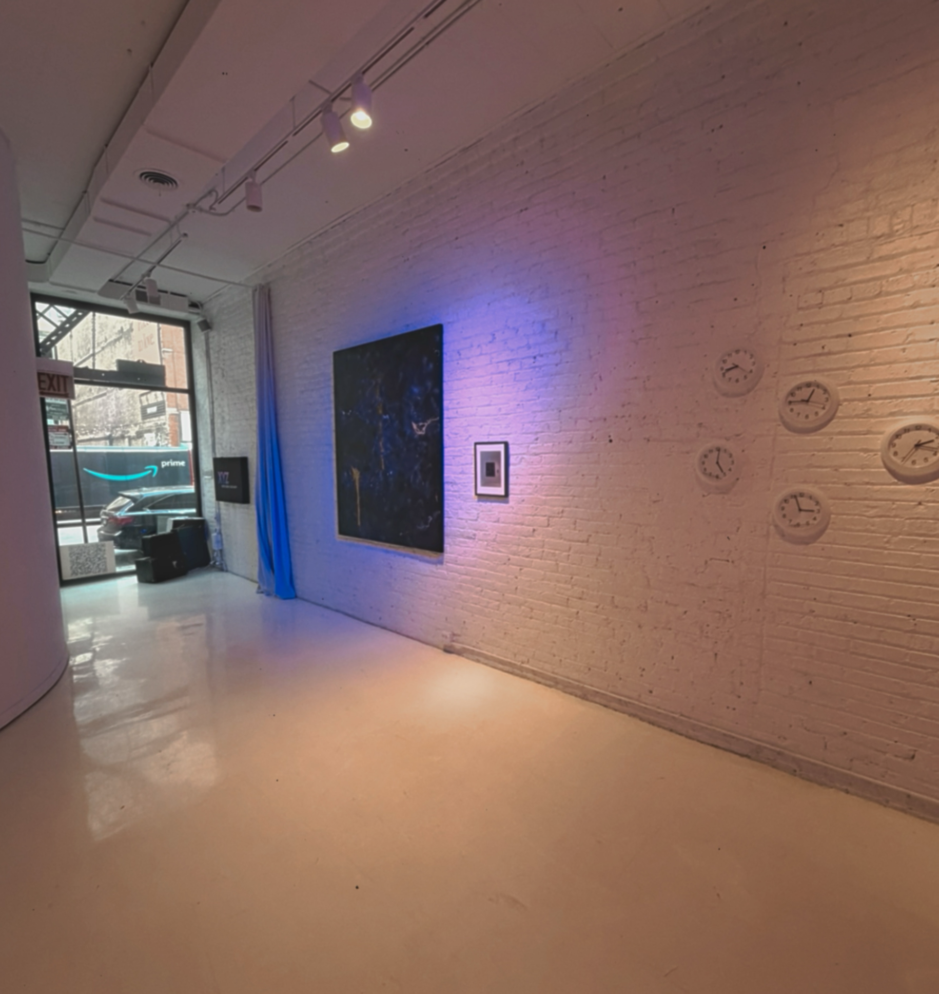 Street facing gallery entrance at XYZ Studios Chicago featuring white brick walls, artwork displays, and large windows in the River North creative studio space.