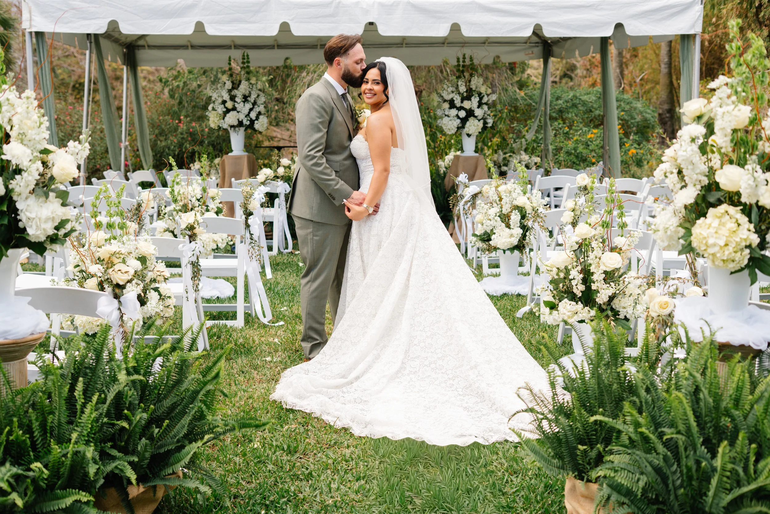 Bride and groom portrait at outdoor wedding ceremony aisle with floral arrangements in South Florida