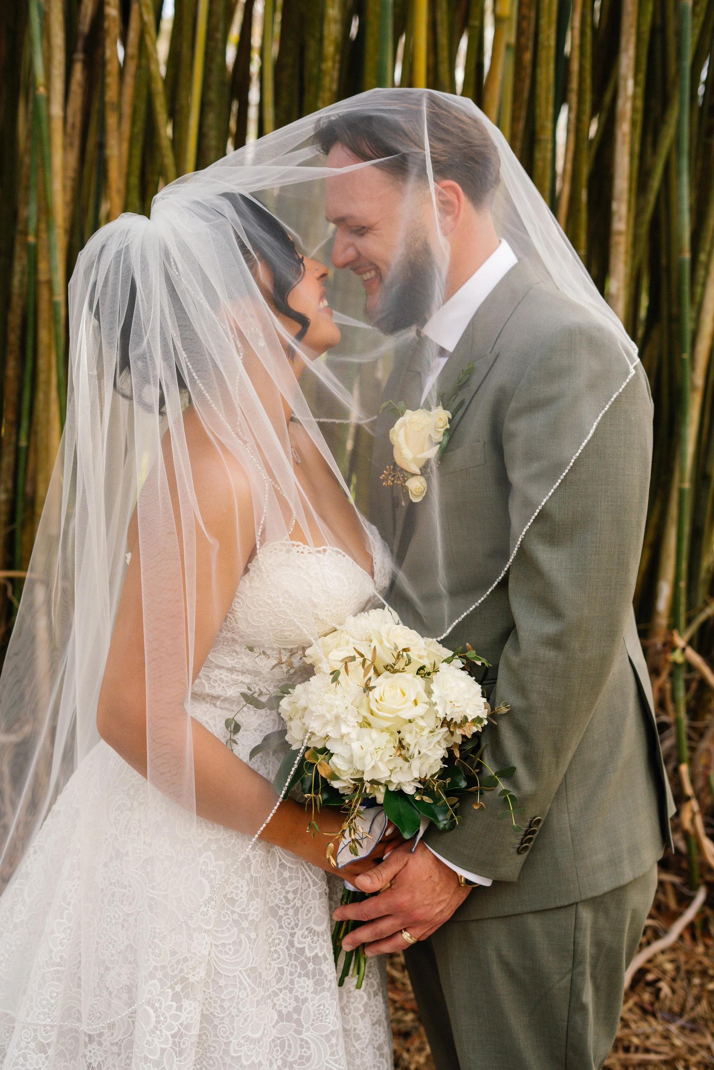 Romantic close-up of bride and groom under veil with bouquet during South Florida wedding