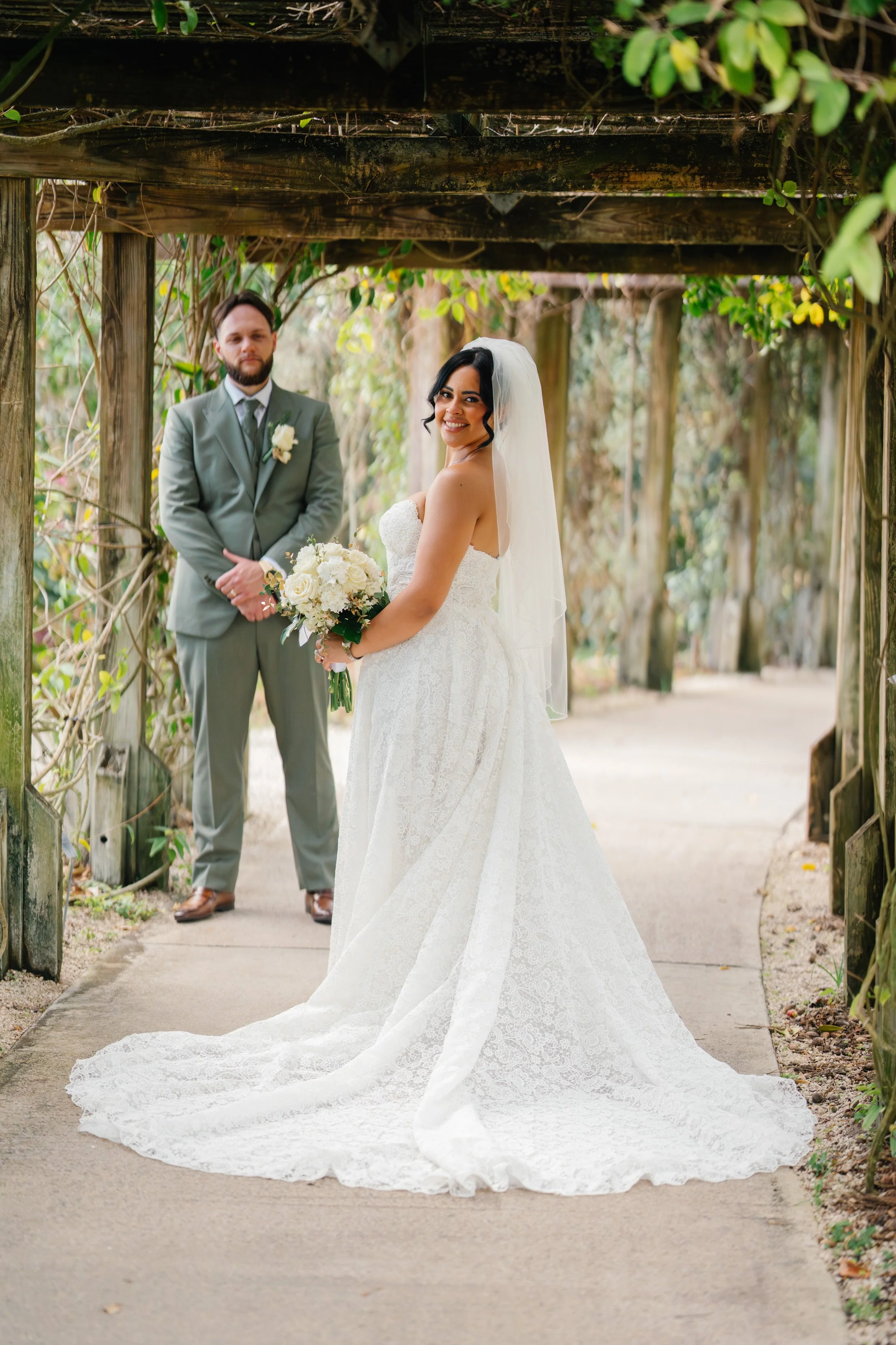Bride and groom standing together under garden archway during South Florida wedding portraits