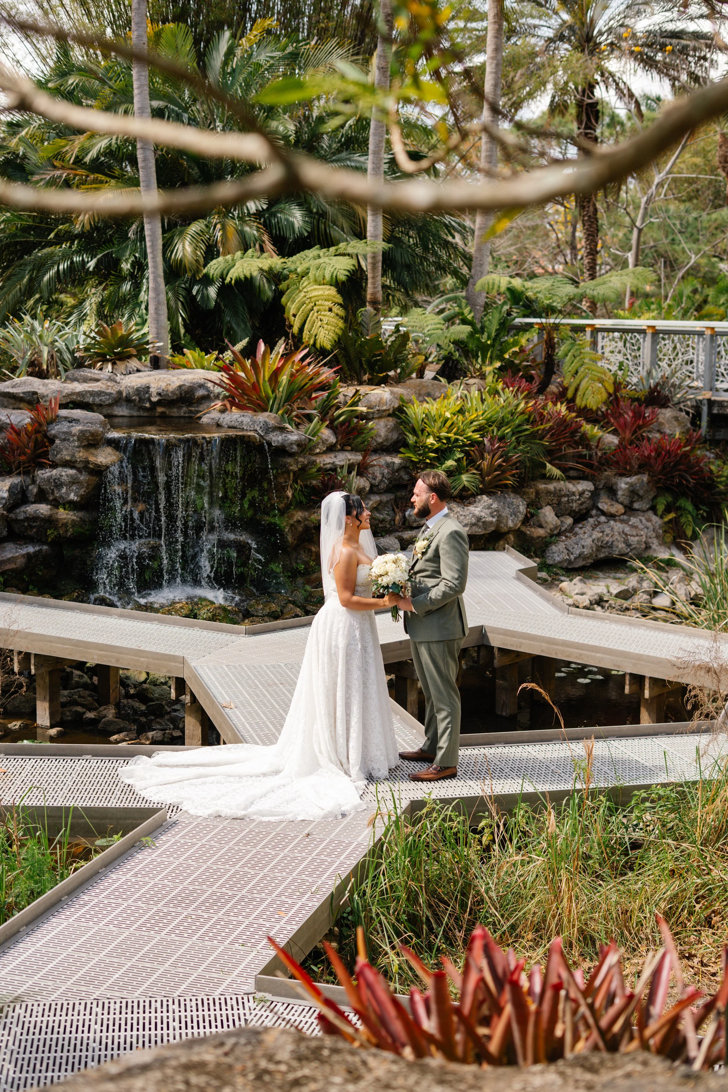 Bride and groom portrait on bridge with waterfall backdrop at South Florida garden wedding venue