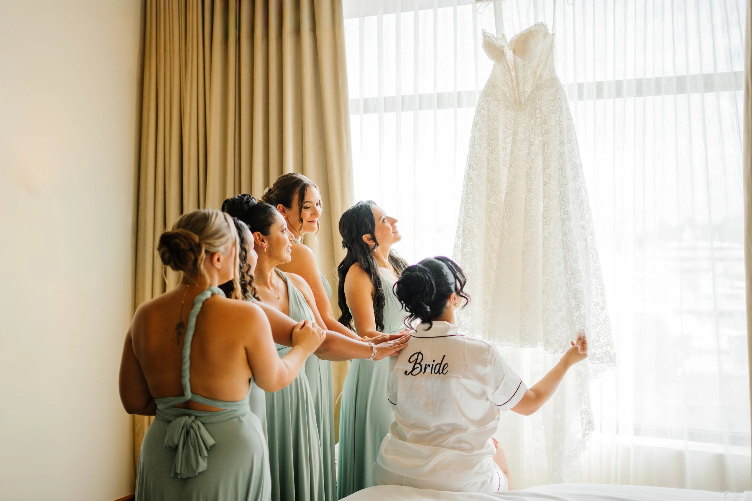 Bridesmaids helping bride get ready with wedding dress in natural light before ceremony in South Florida