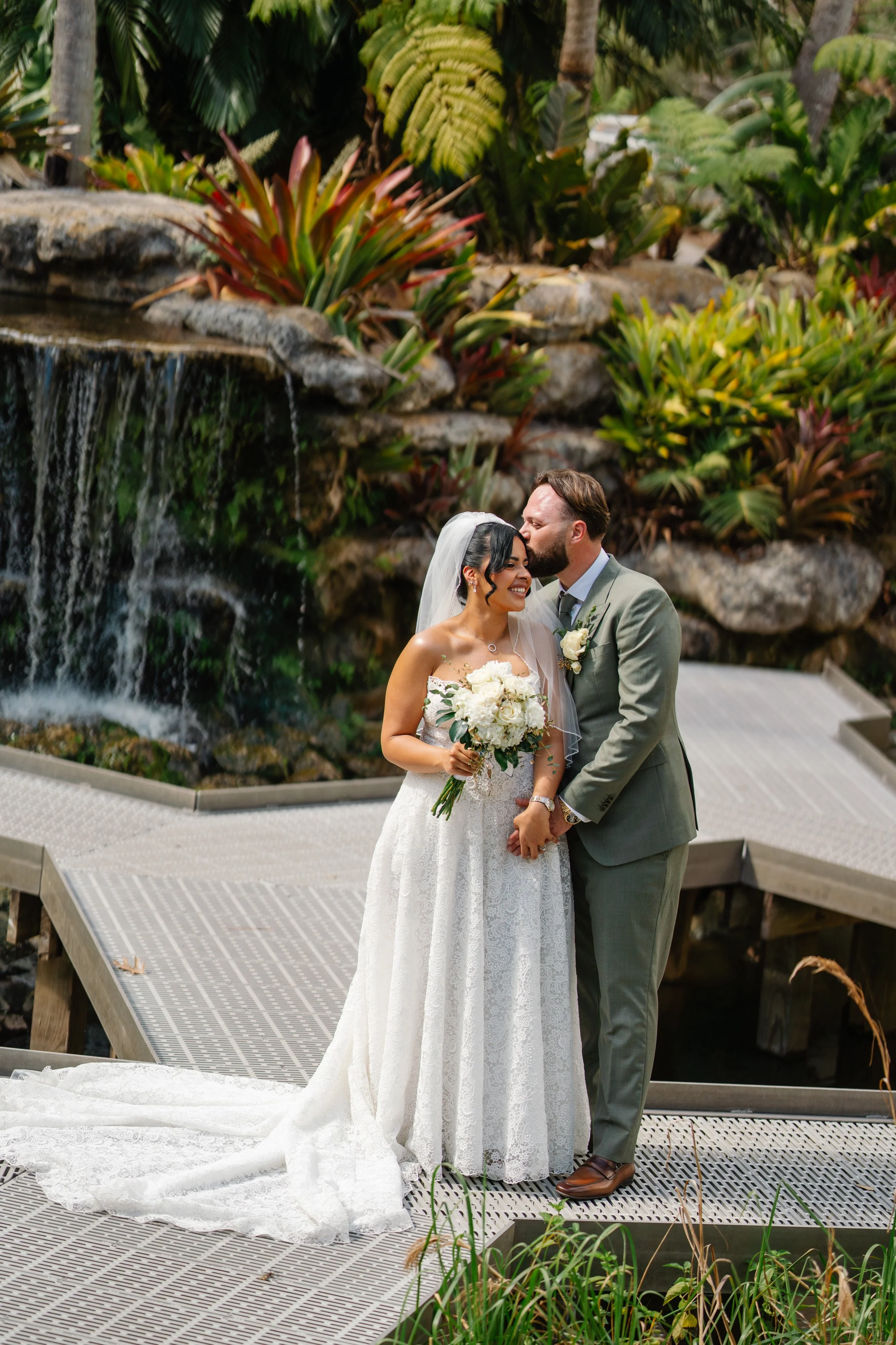 Bride and groom standing together in front of waterfall during South Florida wedding portraits