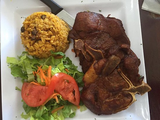 Arroz con gandules, una Chuleta, y lechuga y tomatet. Yellow rice and beans a pork chop, and a small side of lettuce and tomato