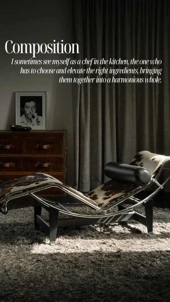 A modern black lounge chair with cowhide pattern, placed on a gray shaggy rug in front of a dark curtain and a wooden dresser. On the wall, there's a quote about 'composition' and a black-and-white photo of a woman.