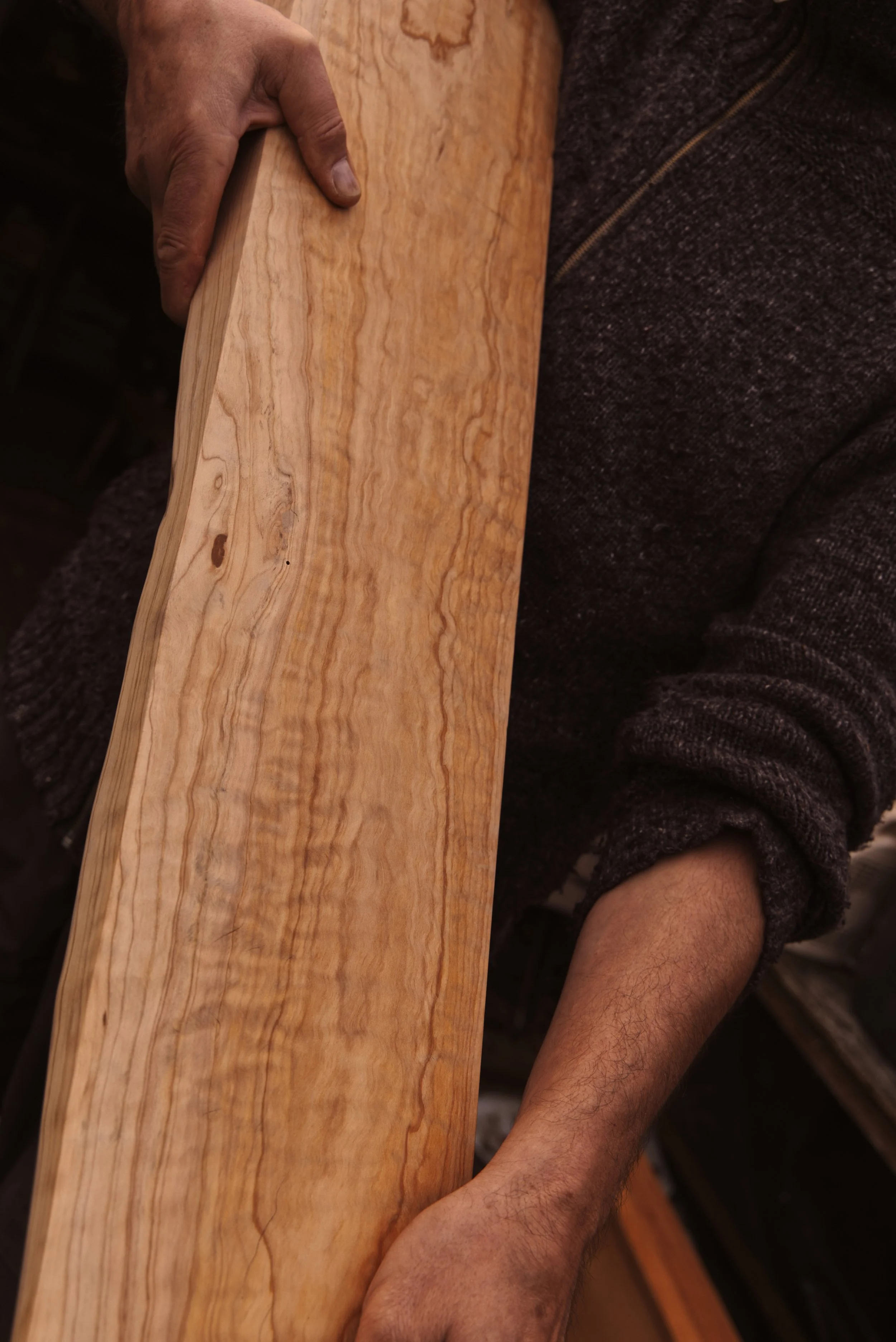 Mannen houdt een stuk lichtgekleurde hout vast met een natuurlijke nerf.