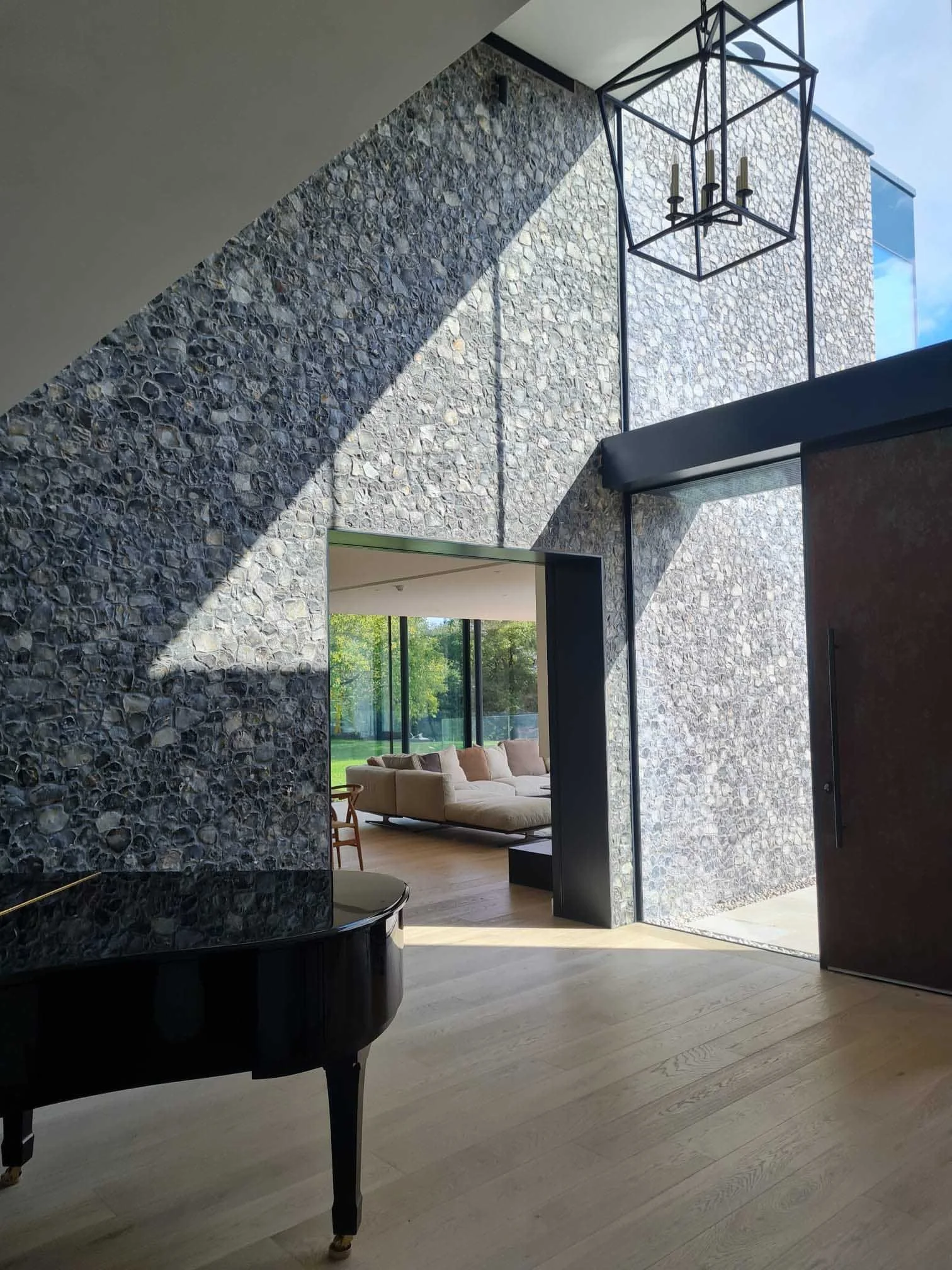 light shining on an internal flint wall with open doorway to dining area and wooden floor