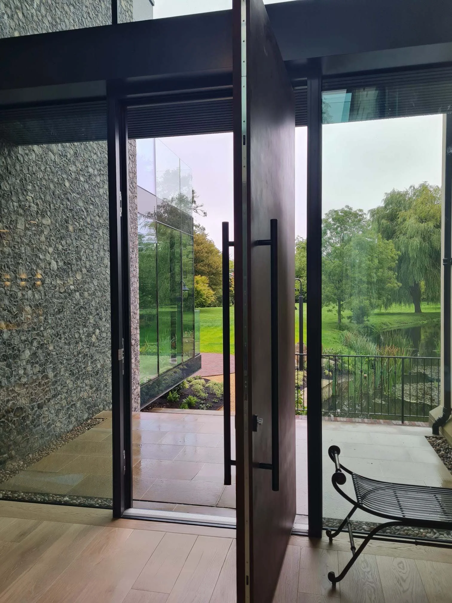 large open front door with flint wall and glazing leading to expansive green lawn