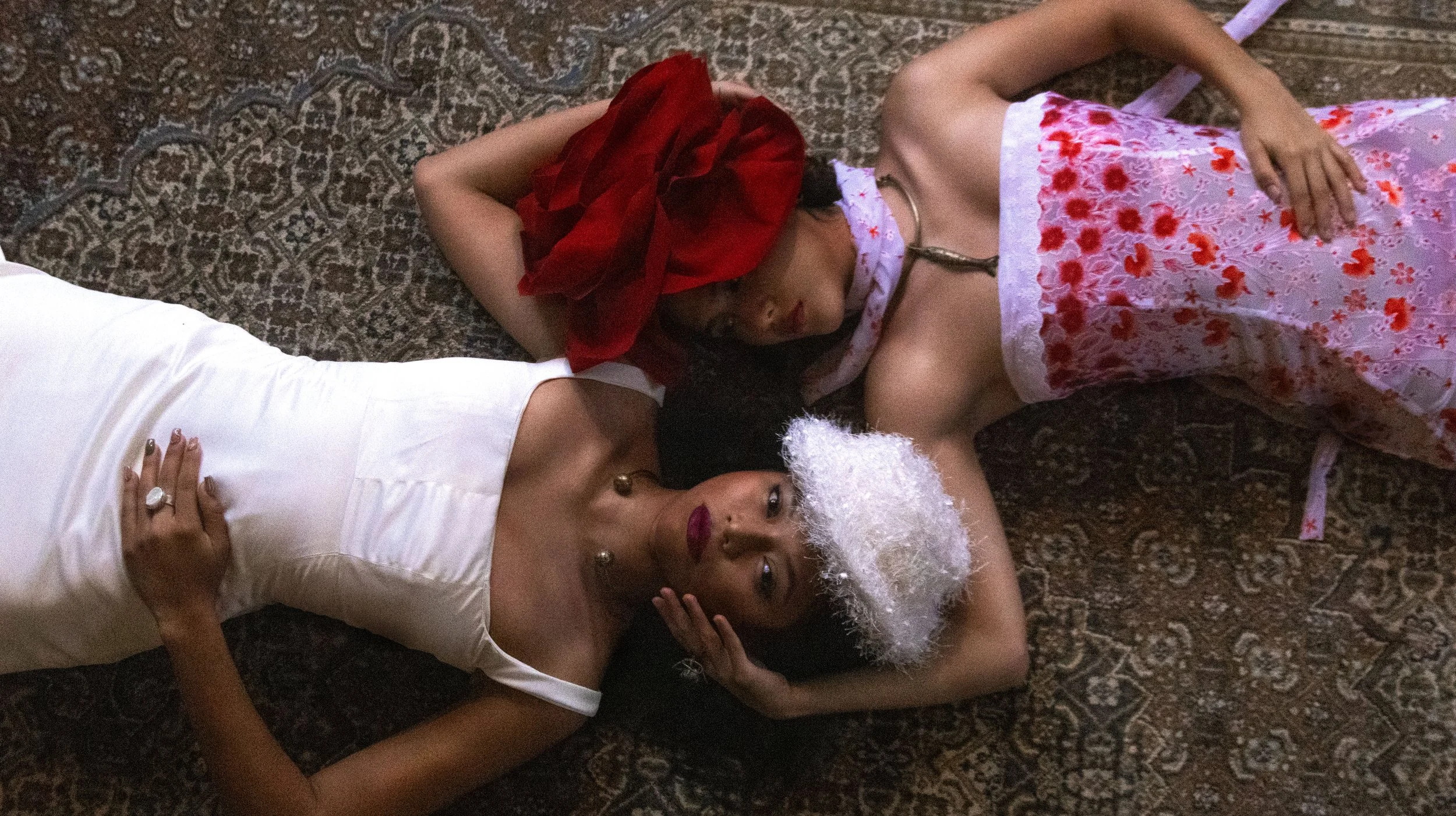Tres mujeres durmiendo en un tapete de palacio, una con vestido blanco, otra con vestido rosa y otra con sombrero rojo.