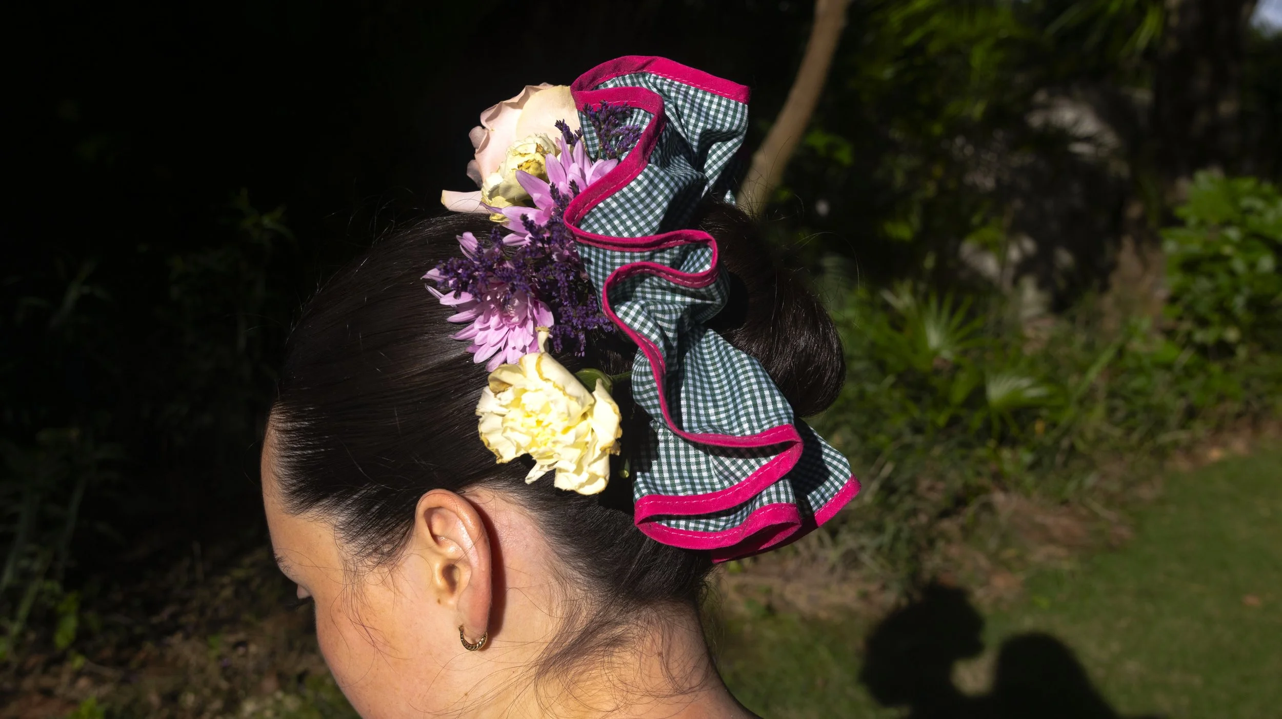 Mujer con peinado adornado con flores y un lazo de tela con check de colores