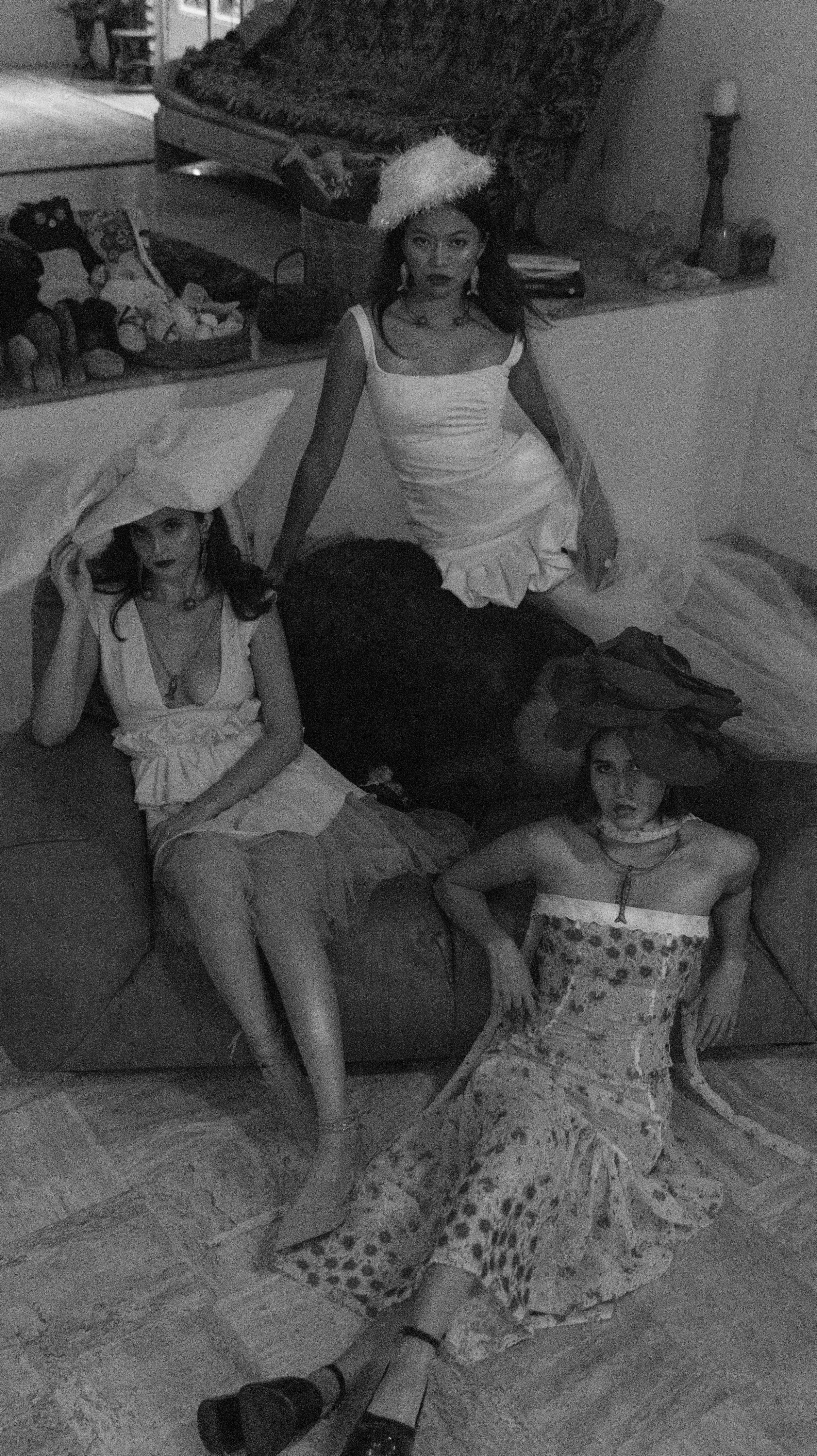 Cuatro mujeres vestidas con ropa llamativa y accesorios en un ambiente interior, posando en diferentes posiciones.