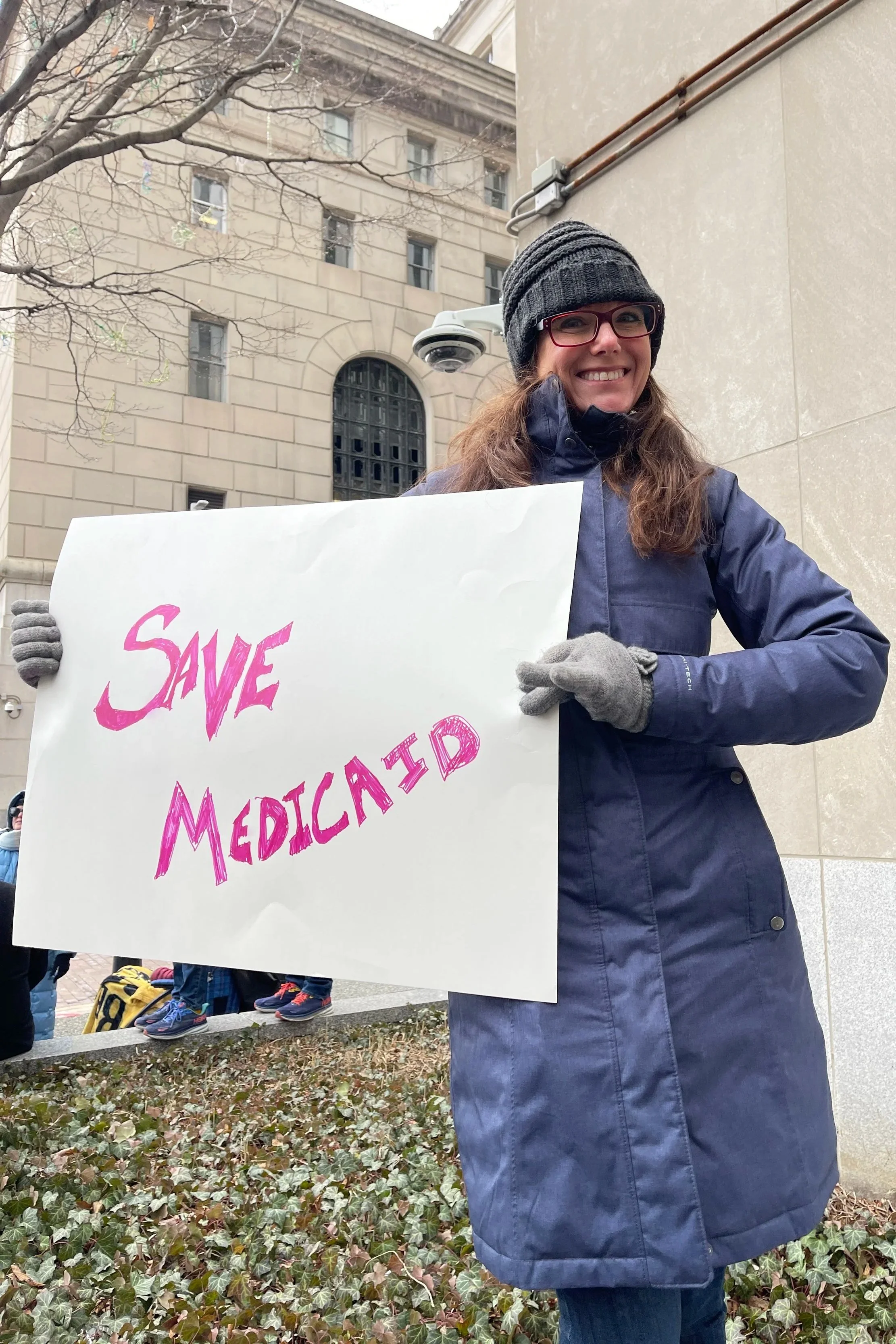 Rebecca MacTaggart holds a "Save Medicaid" sign at a protest in downtown Pittsburgh.