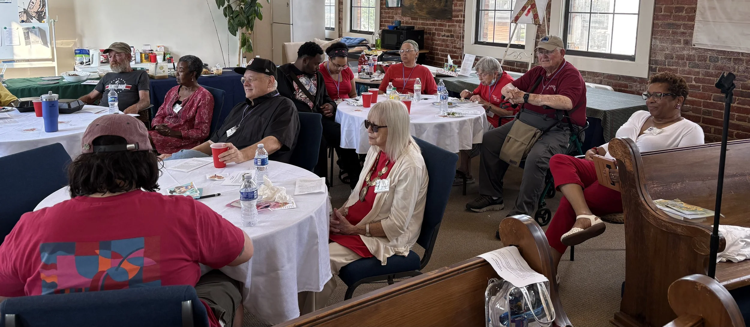 several people are seated around two round tables with white tablecloths