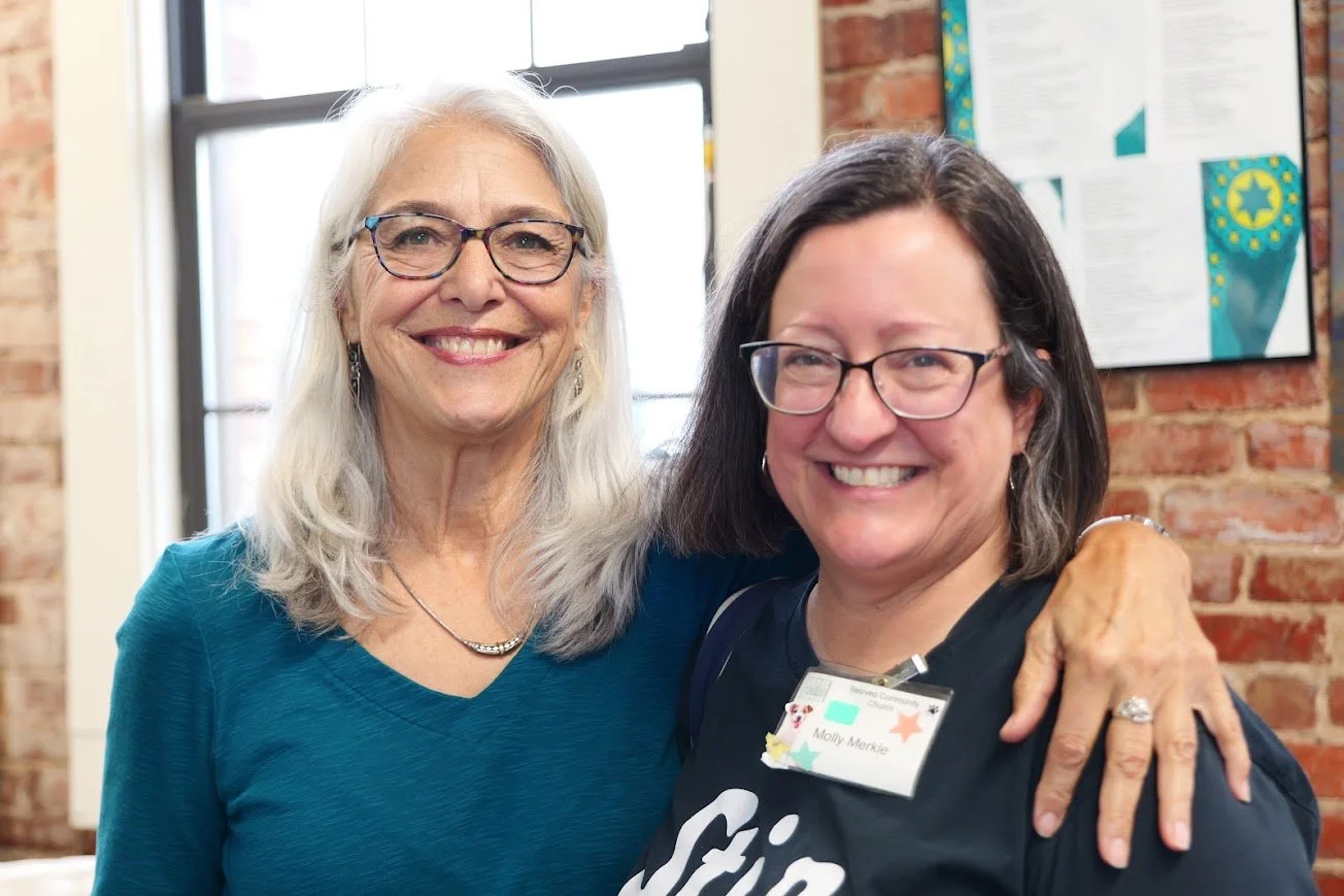 two women are smiling warmly at the camera