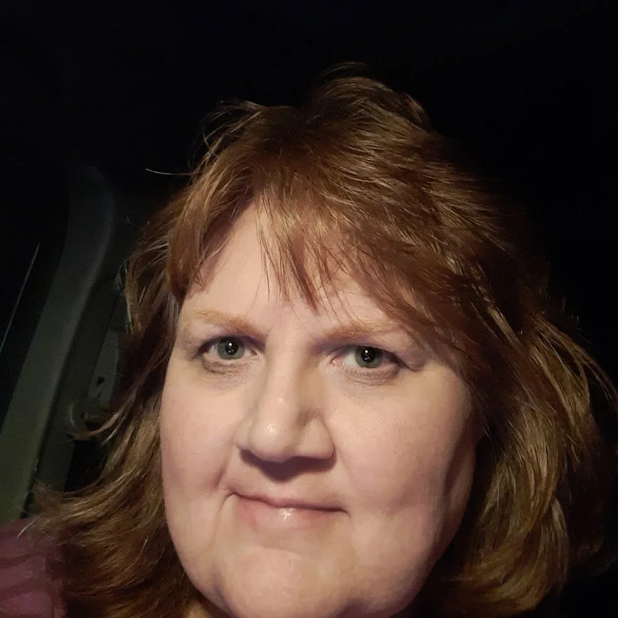 a woman with brown hair smiles slightly