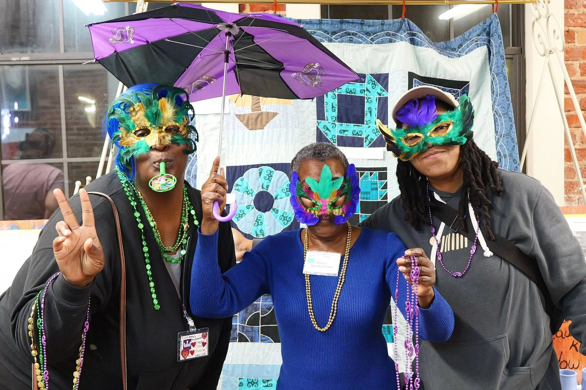 three people are wearing Mardi Gras masks and holding up peace signs