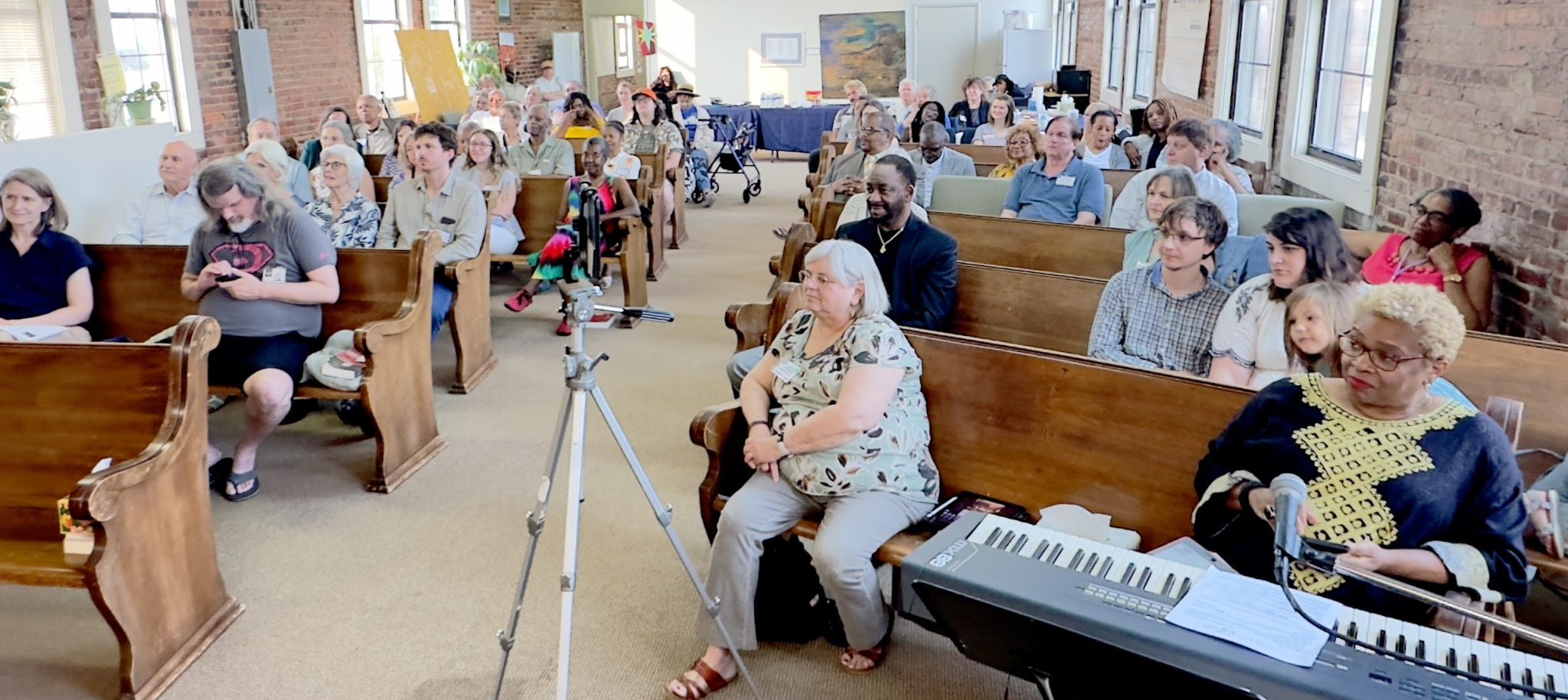 several people are sitting on church pews listening to a speaker