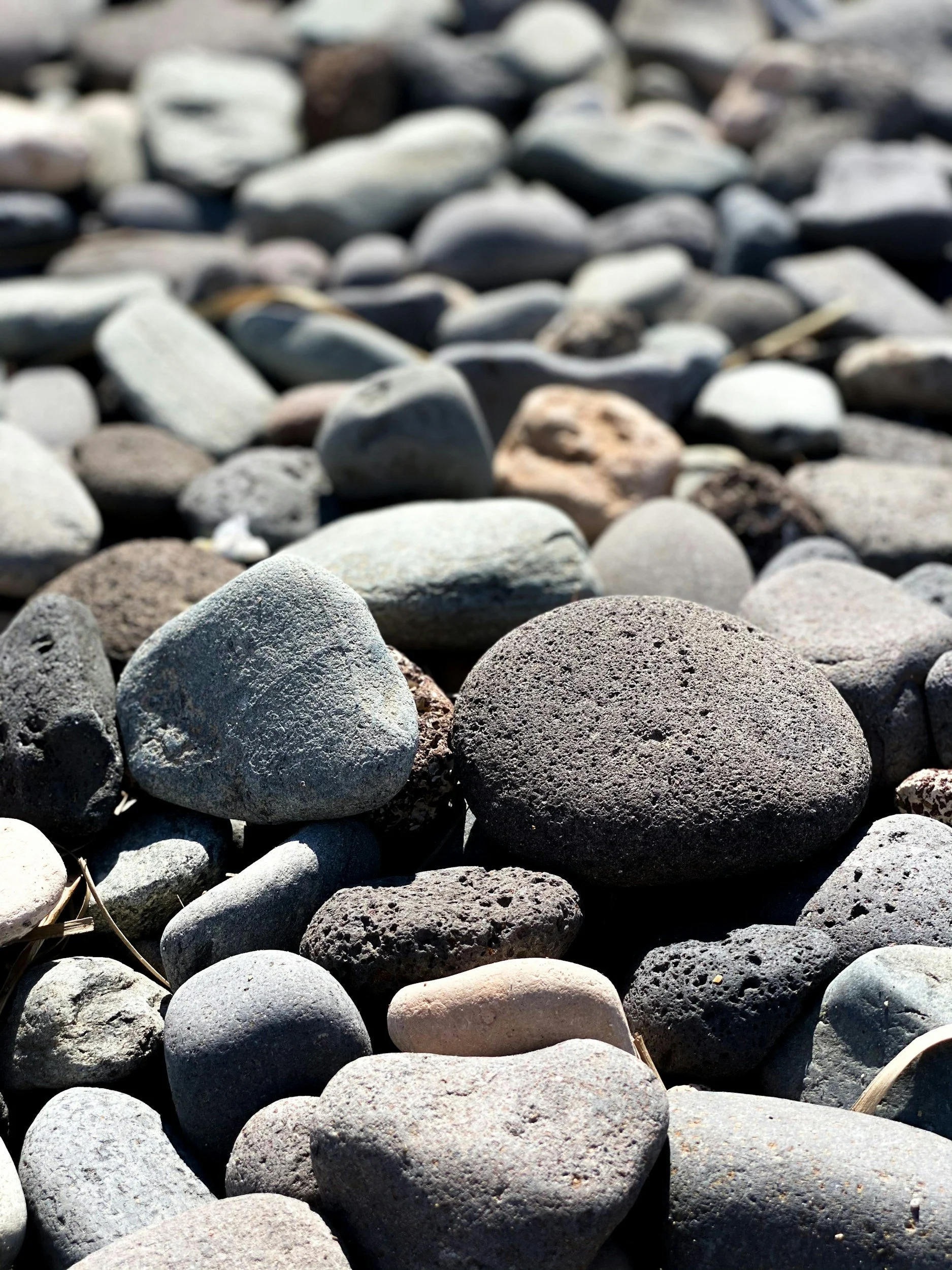 Close-up of smooth, rounded rocks and pebbles on a beach.